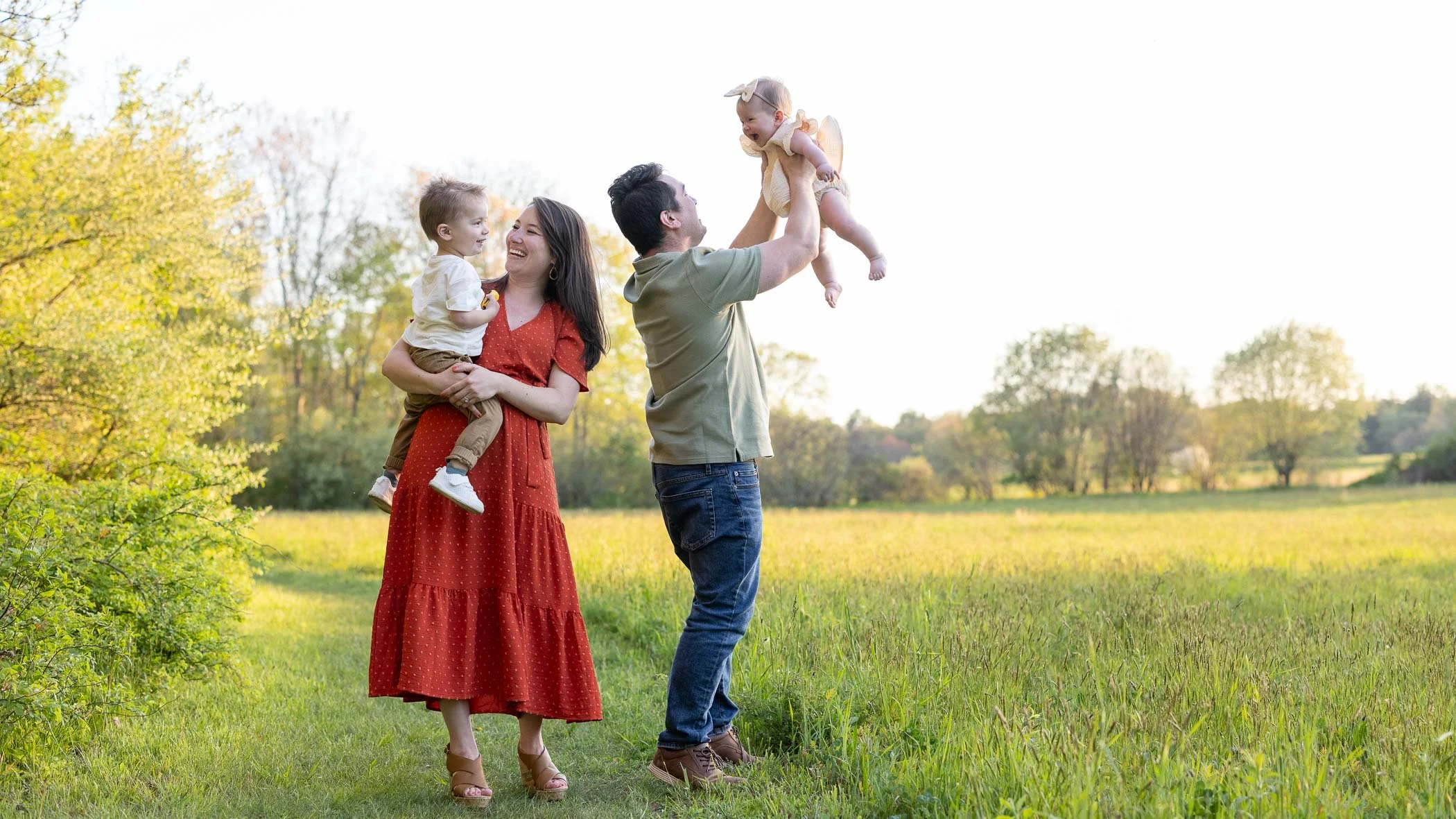 Smiling mom and dad play with son and daughter in open field