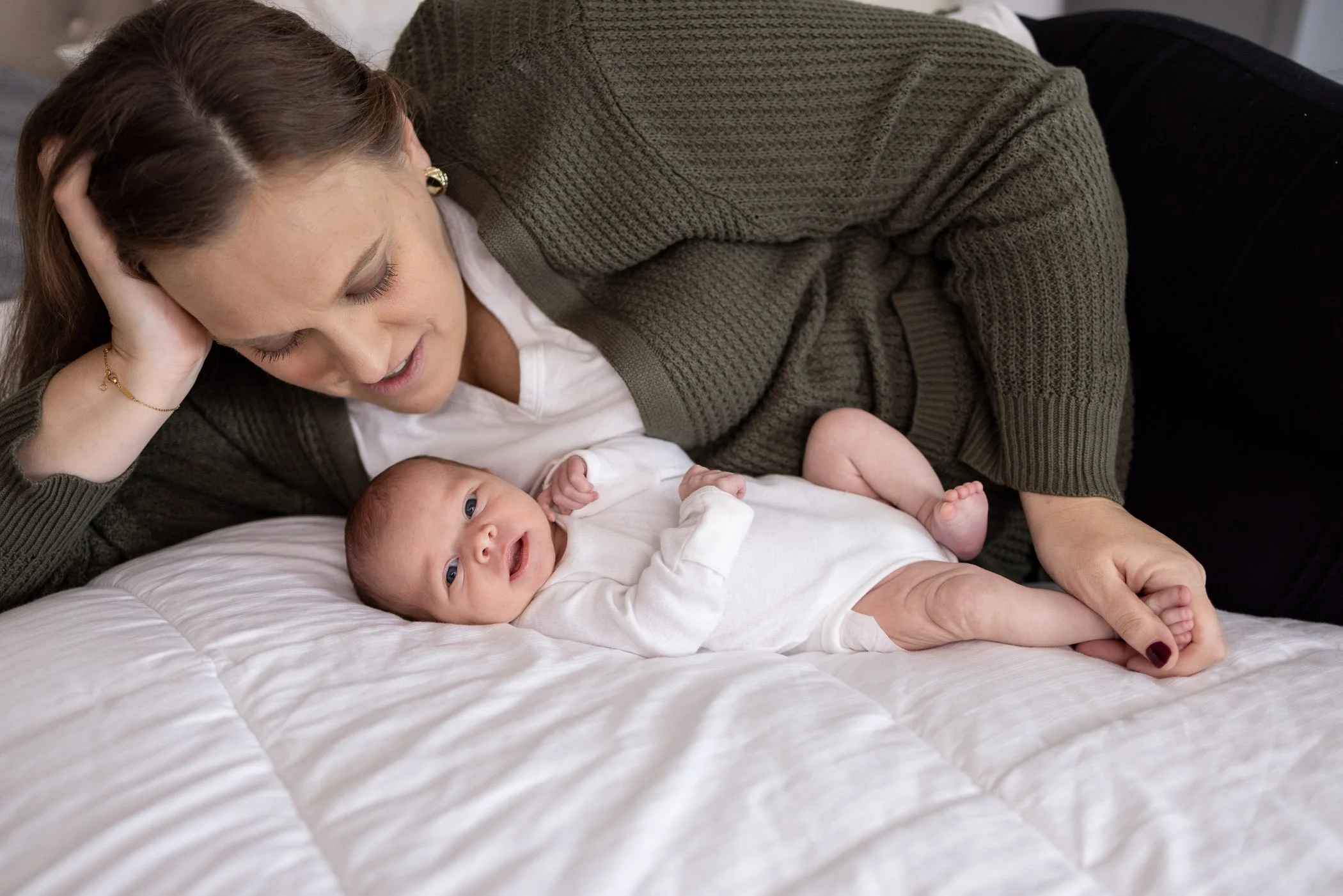 Mother of newborn baby laying on a bed adoring her new daughter