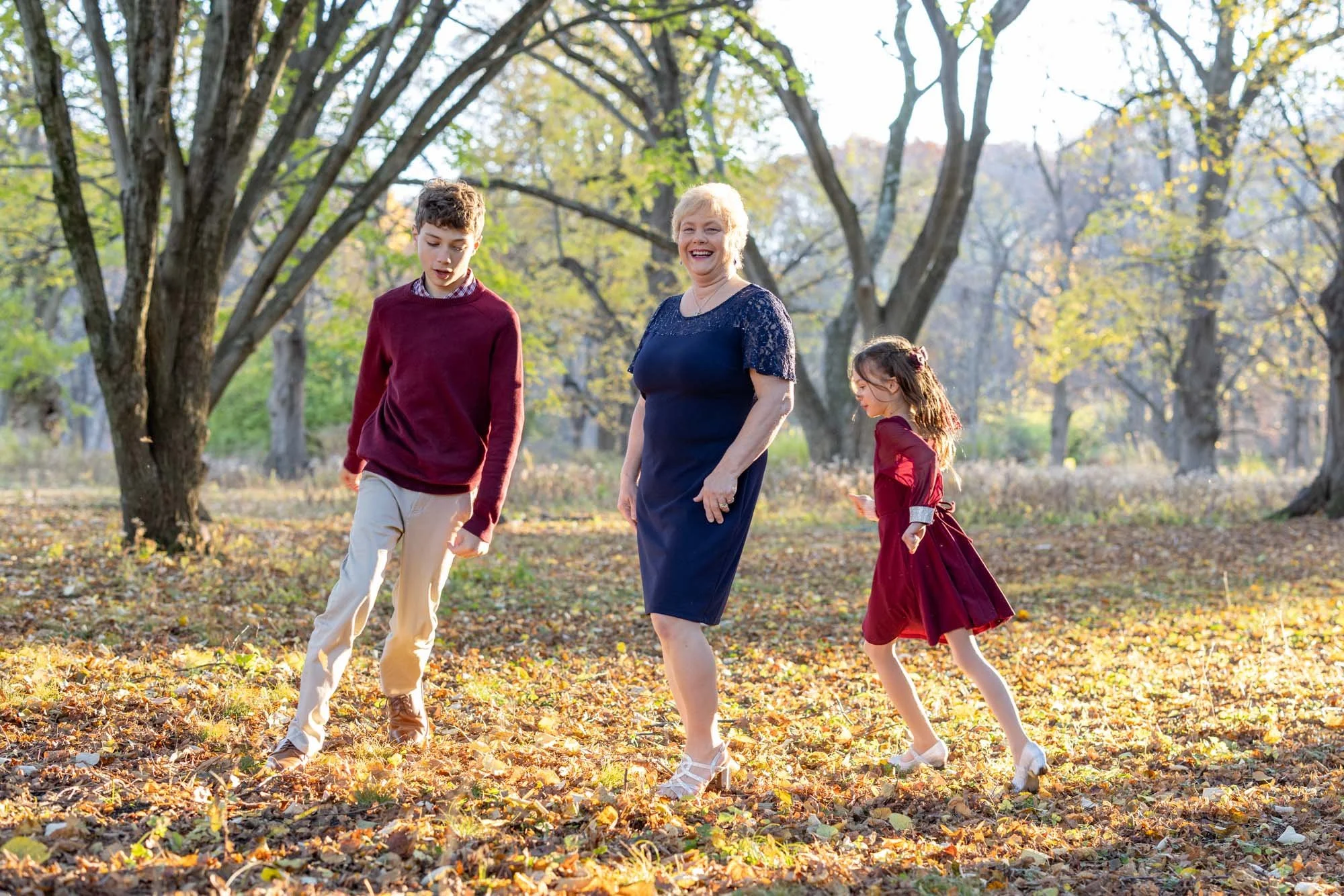 grandson and granddaughter run around grandmother in pretty light