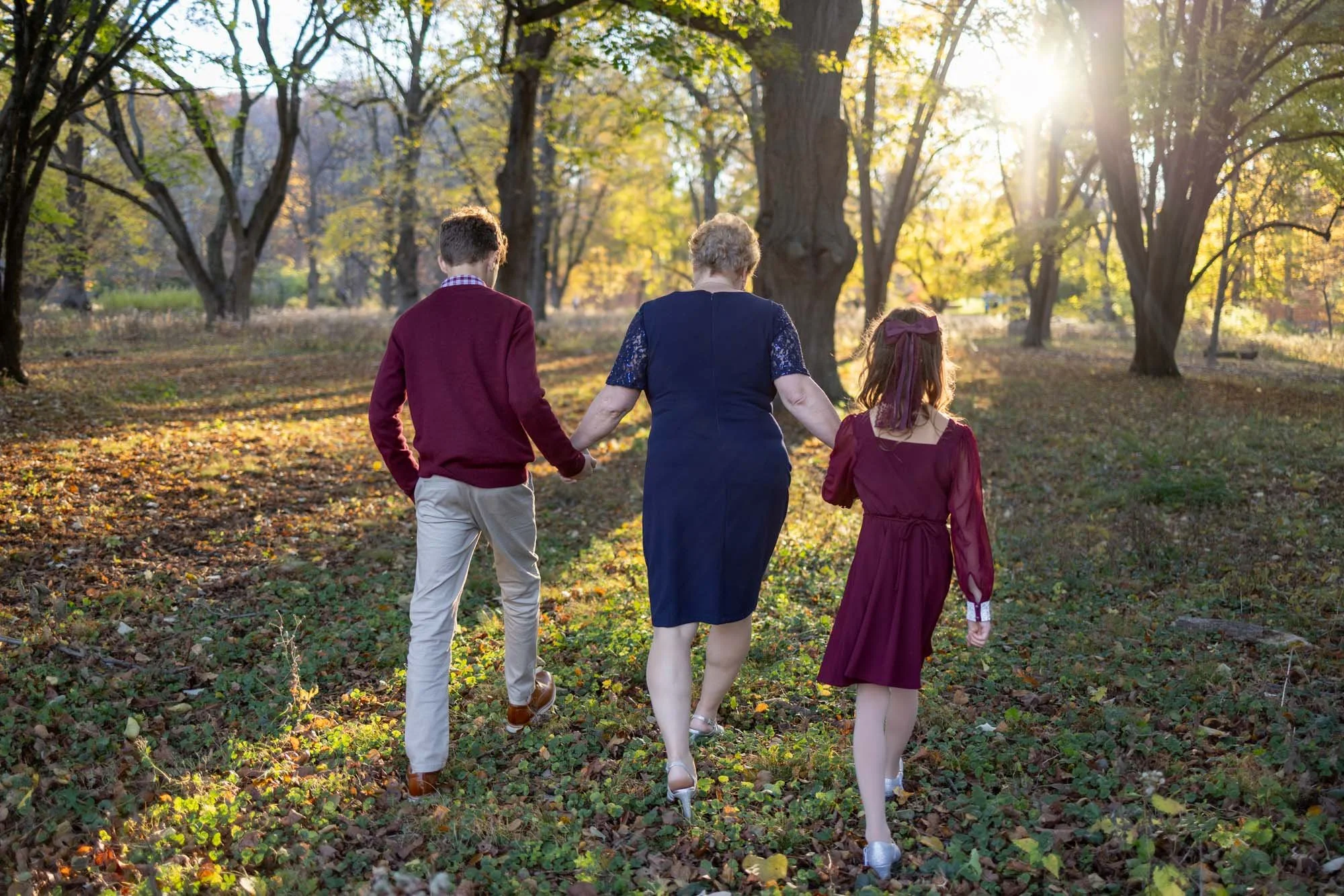 grandson grandmother and granddaughter walking in the woods with fall colors