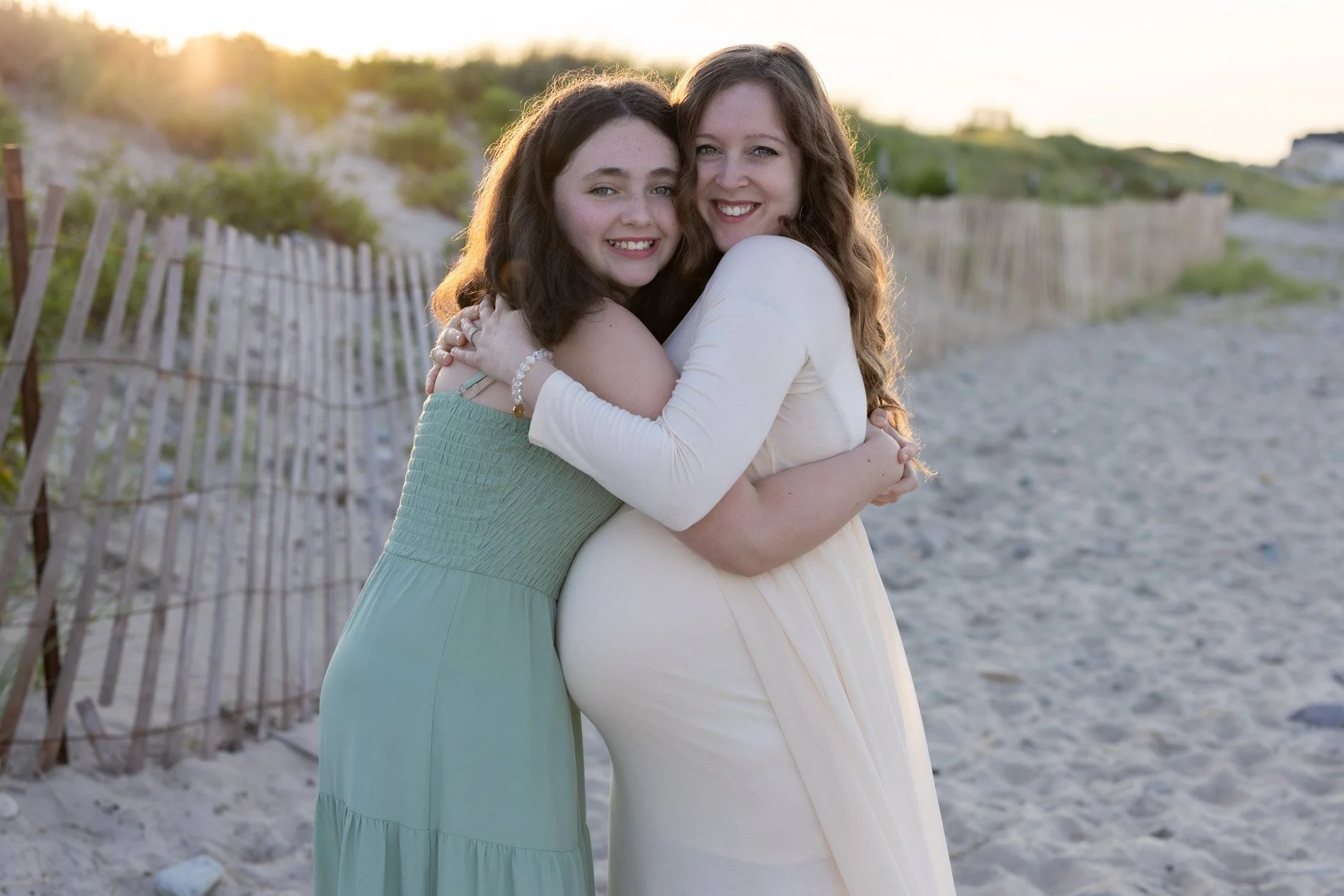 daugher-and-pregnant-mom-embrace-in-big-hug-on-beach.jpg