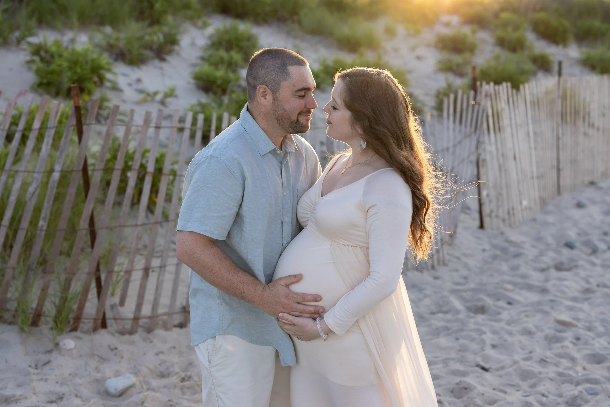 Husband holds wife's pregnant belly gaze at each other