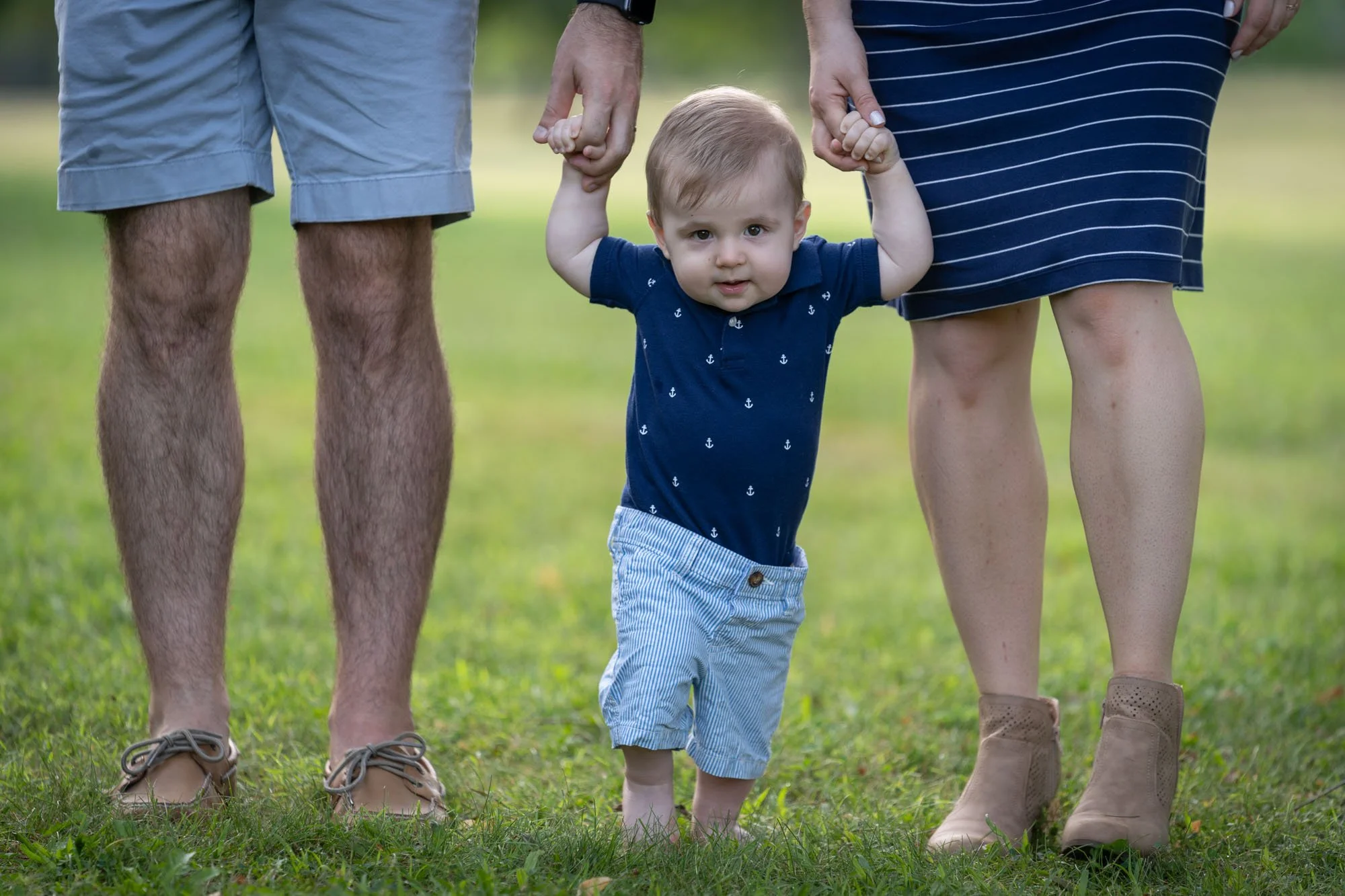 Dad, baby son and mom holding hands walking.