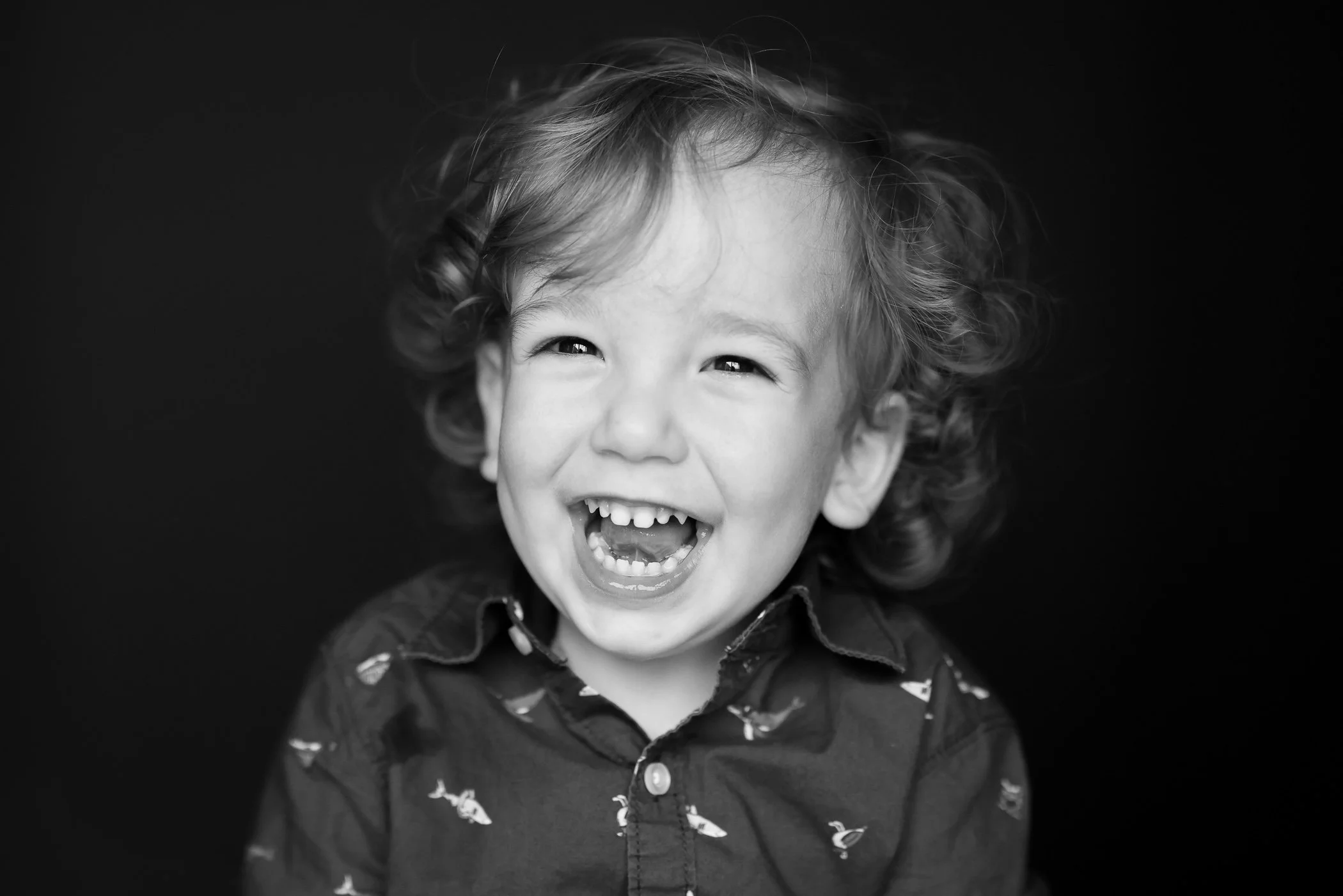 happy young boy laughing with black background