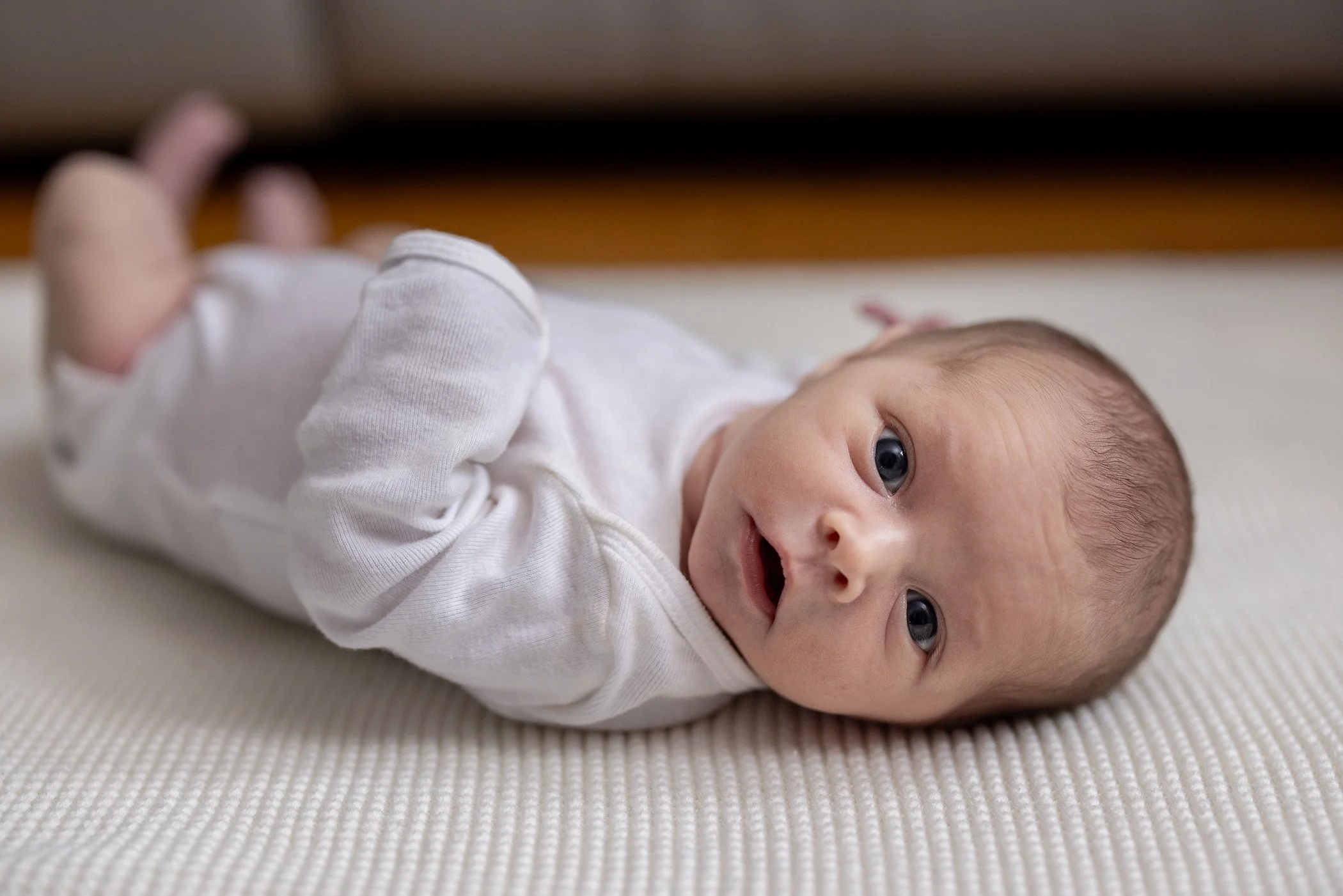 Newborn baby girl laying on back looking at camera