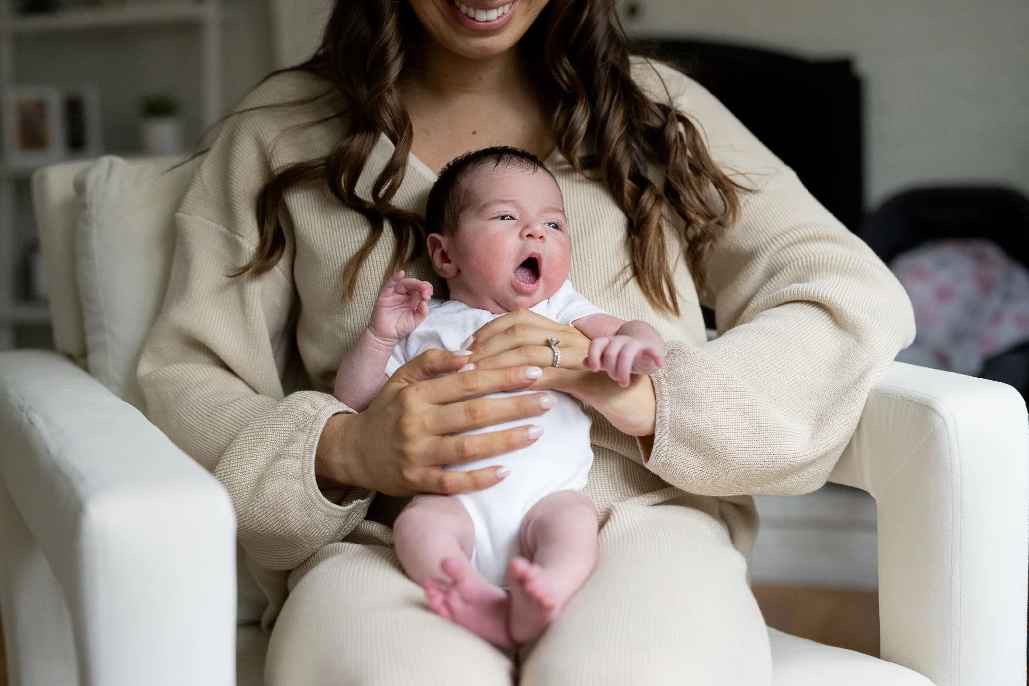 Newborn girl had big yawn while sitting in mom's lap