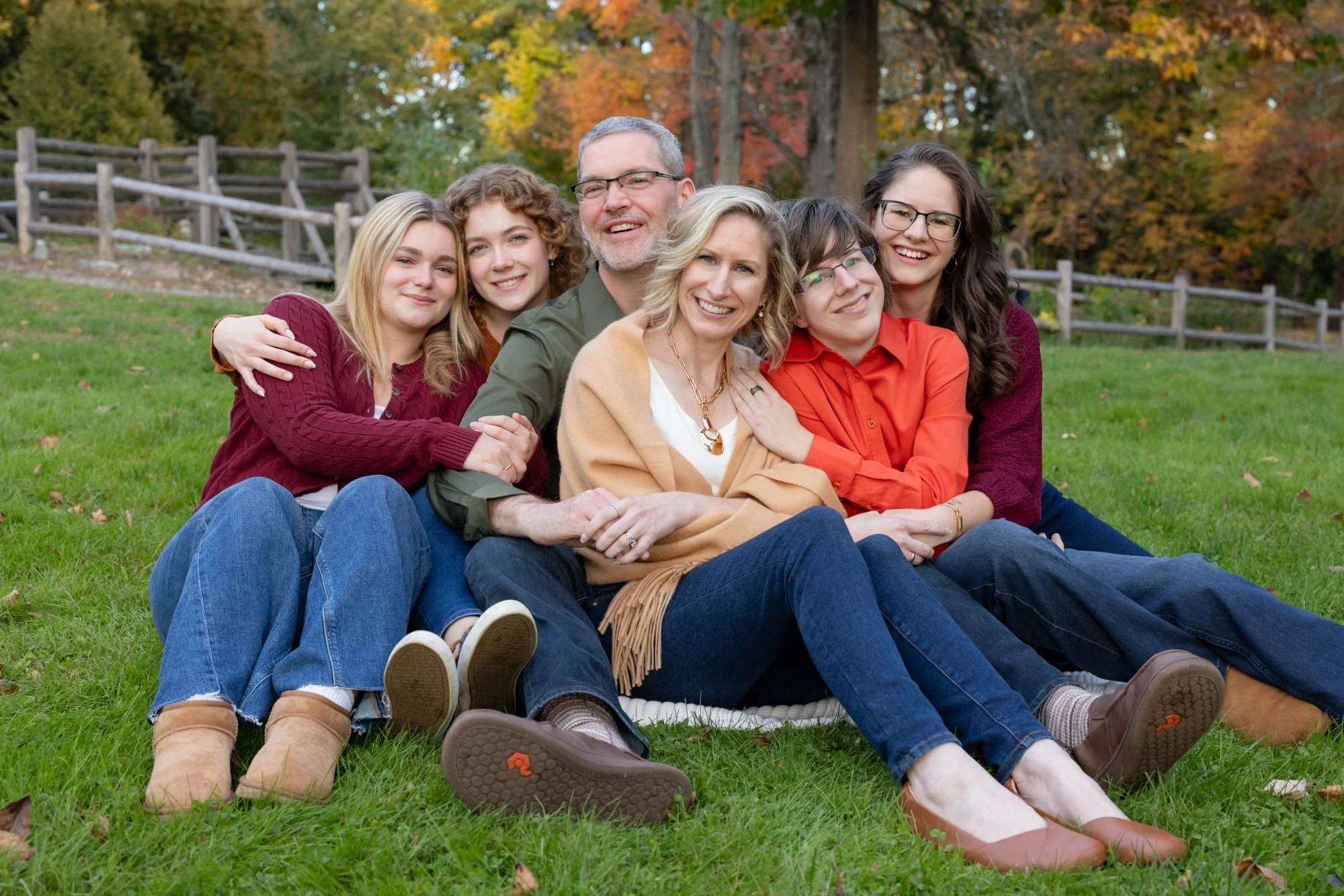 family with adult children cuddle together in park.jpg