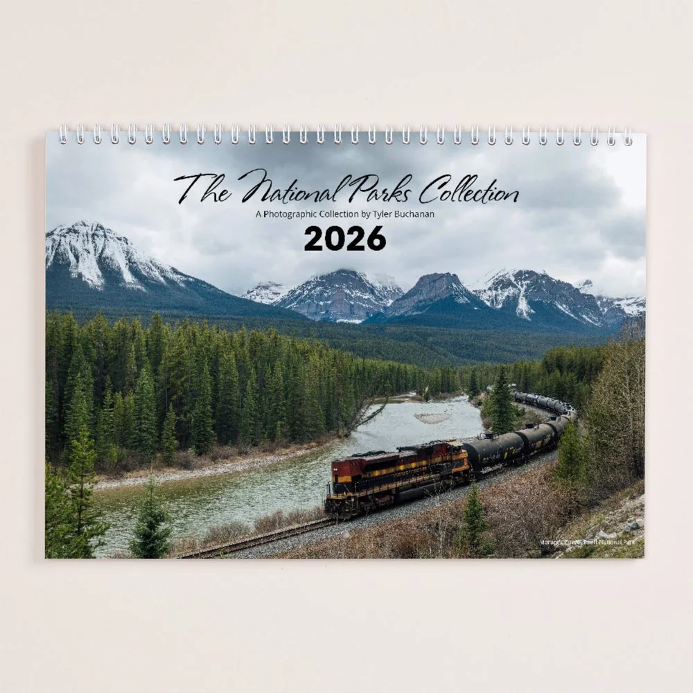 2026 calendar with a scenic mountain landscape, river, forest, and a train in the foreground.