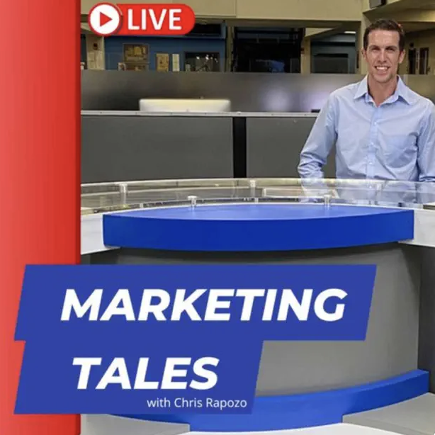 A man in a light blue shirt standing in a newsroom behind a news desk with a blue and gray design, with a red 'LIVE' icon in the top left corner and the text 'Marketing Tales with Chris Rapozo' displayed on the desk.