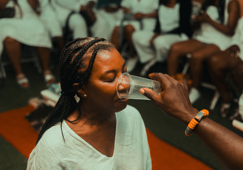 A traveler tasting water during the water/drink ritual at a naming ceremony in Ghana