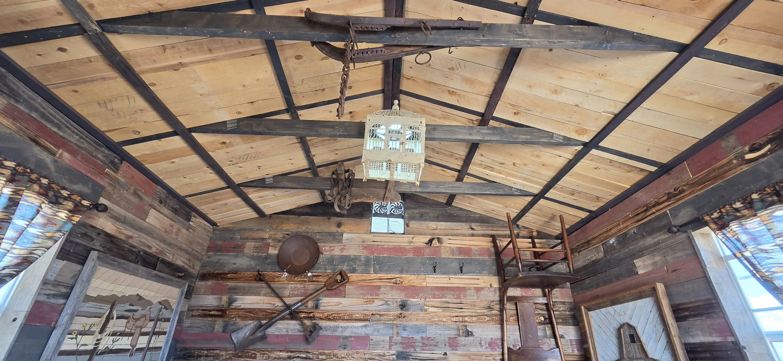 full ceiling shot showing trusses and light wood ceiling. also showing the lamp and the wall art.
