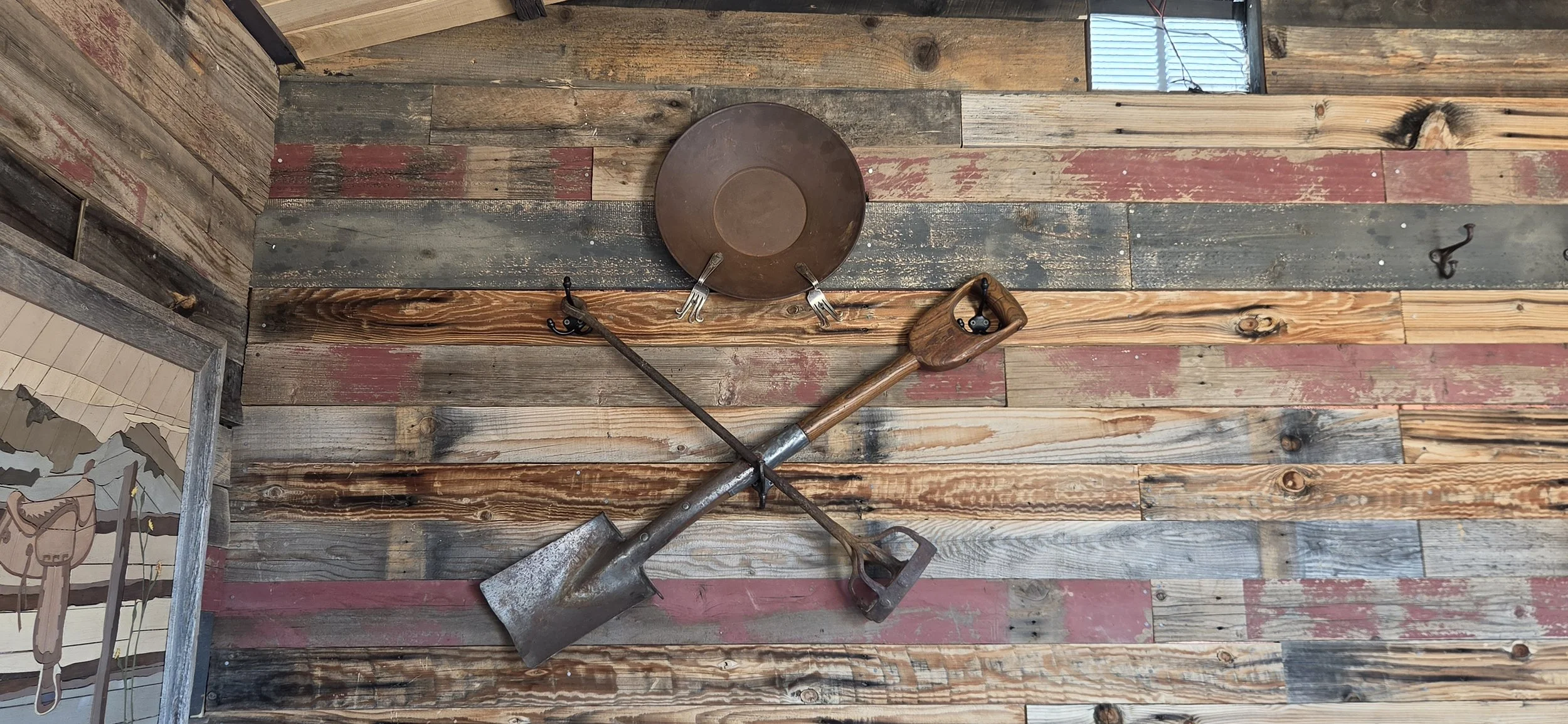 Vintage miners shovel crossed with a vintage branding iron with a miners gold pan above the tools.