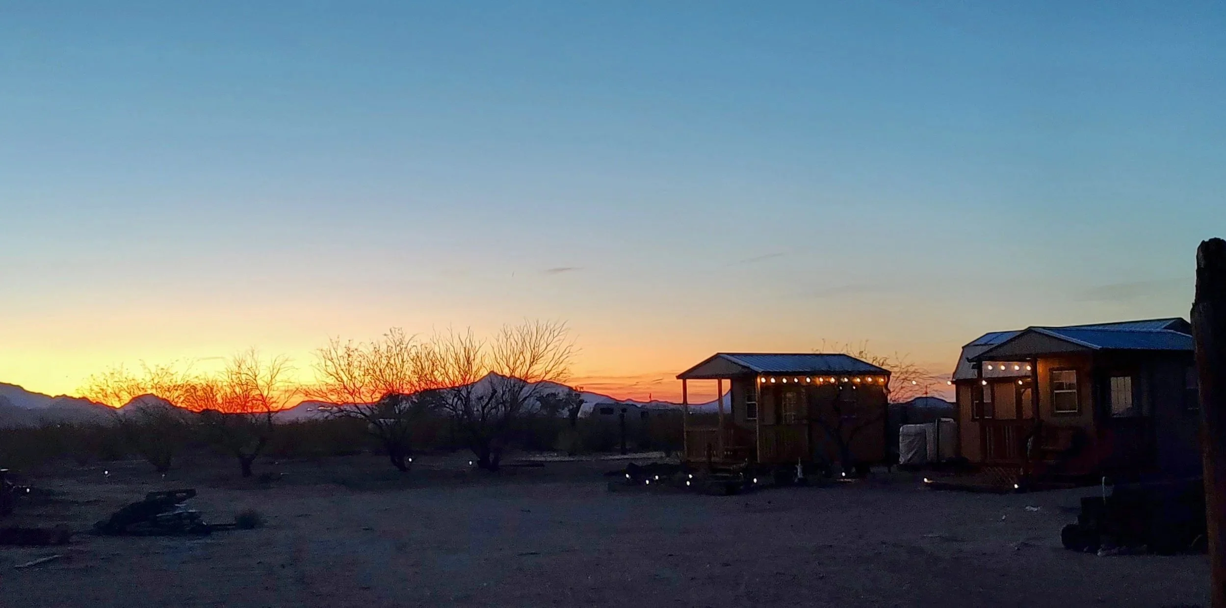 Twilight in the Sonoran Desert at Mesquite Haven. In the foreground you can see the bunkhouses, The Cannonball and The Eastwood. You can also see all the small solar lights twinkling around.