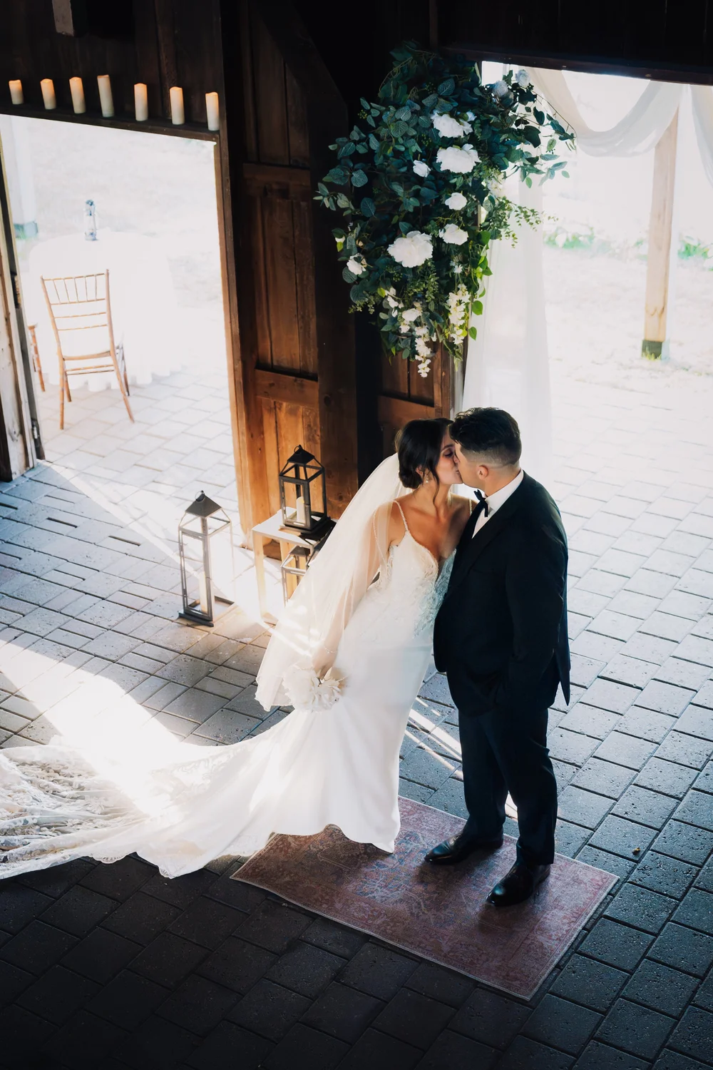 Bride and groom kissing indoors under florals