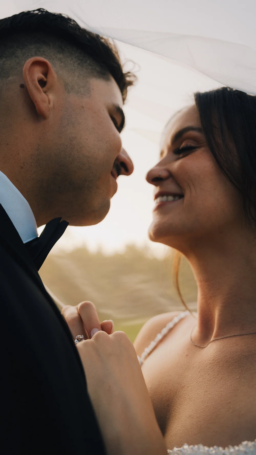 Couple smiling with a veil blowing behind them