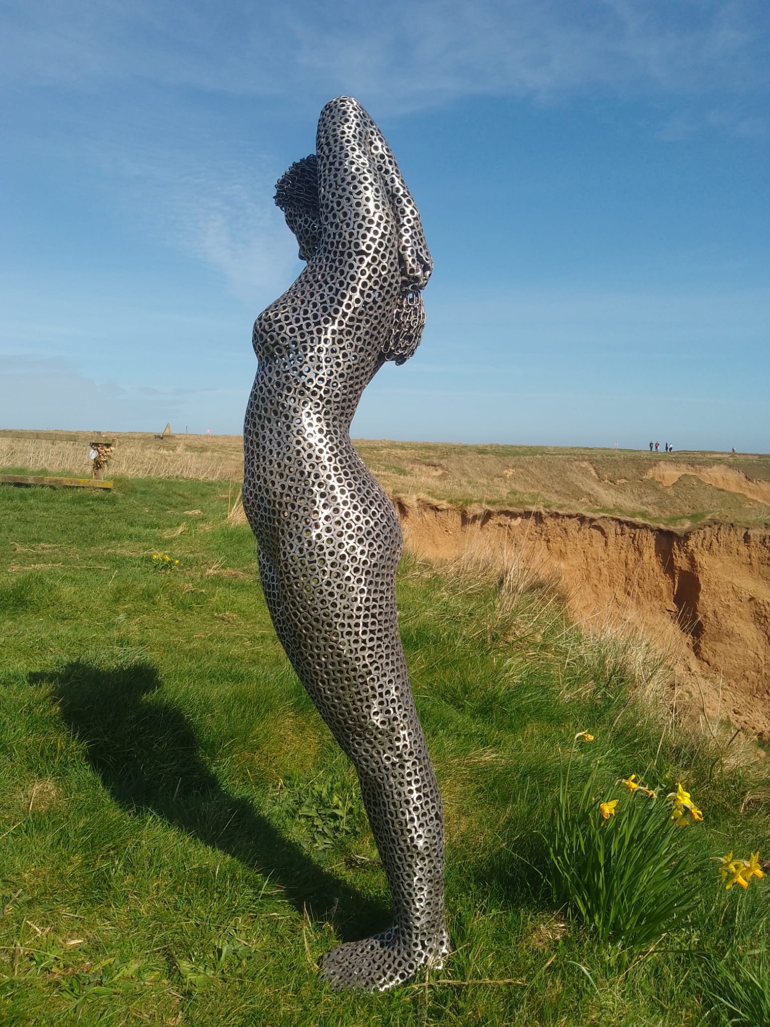 Woman-shaped sculpture in motion, welded from steel nuts with a matte silver finish. Appears to float, radiating strength and elegance.