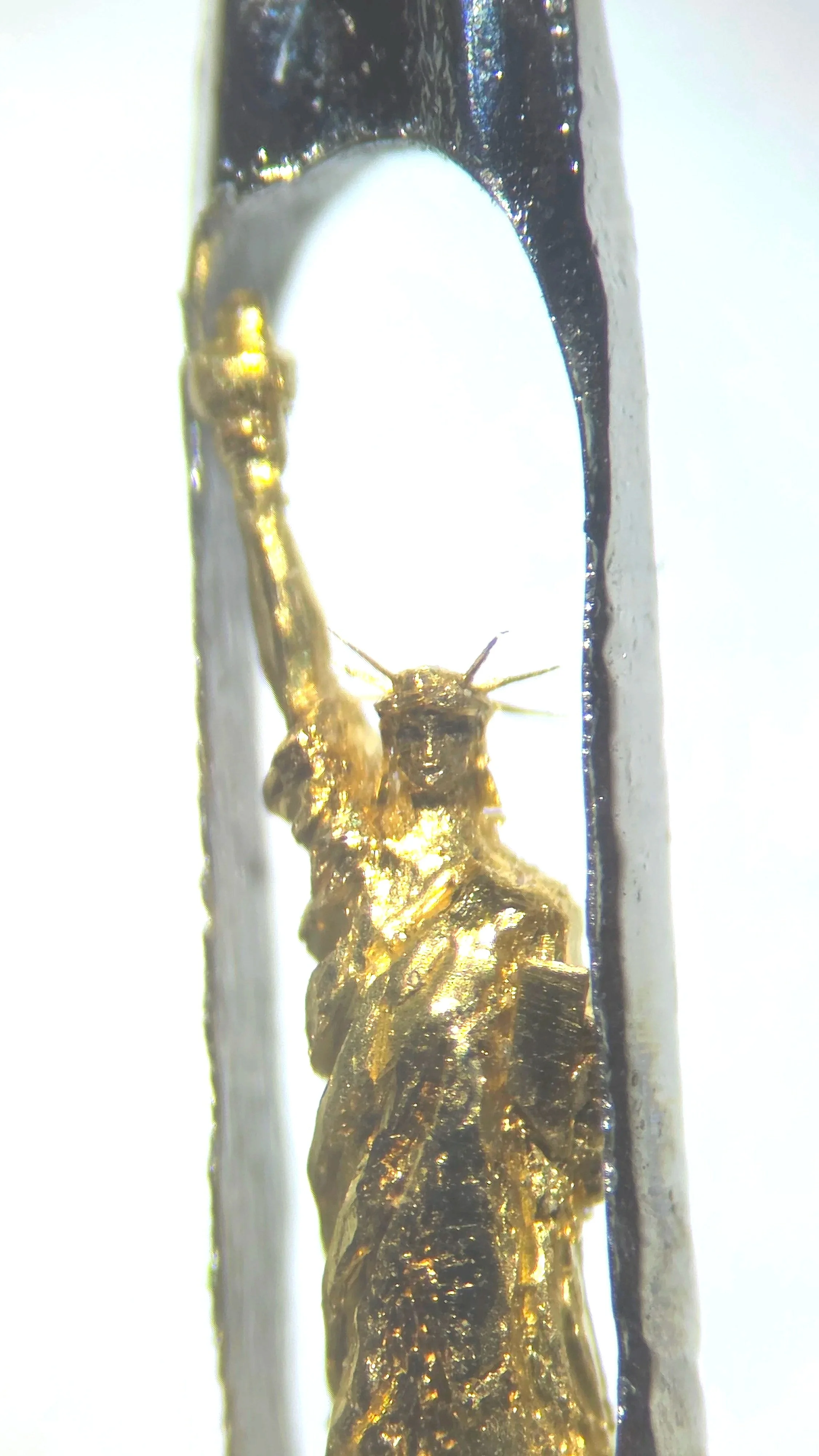 Close-up / Microscope View of the Sculpture 22 carat gold Statue of Liberty micro sculpture by Dr Willard Wigan MBE viewed through microscope, housed within the eye of a needle