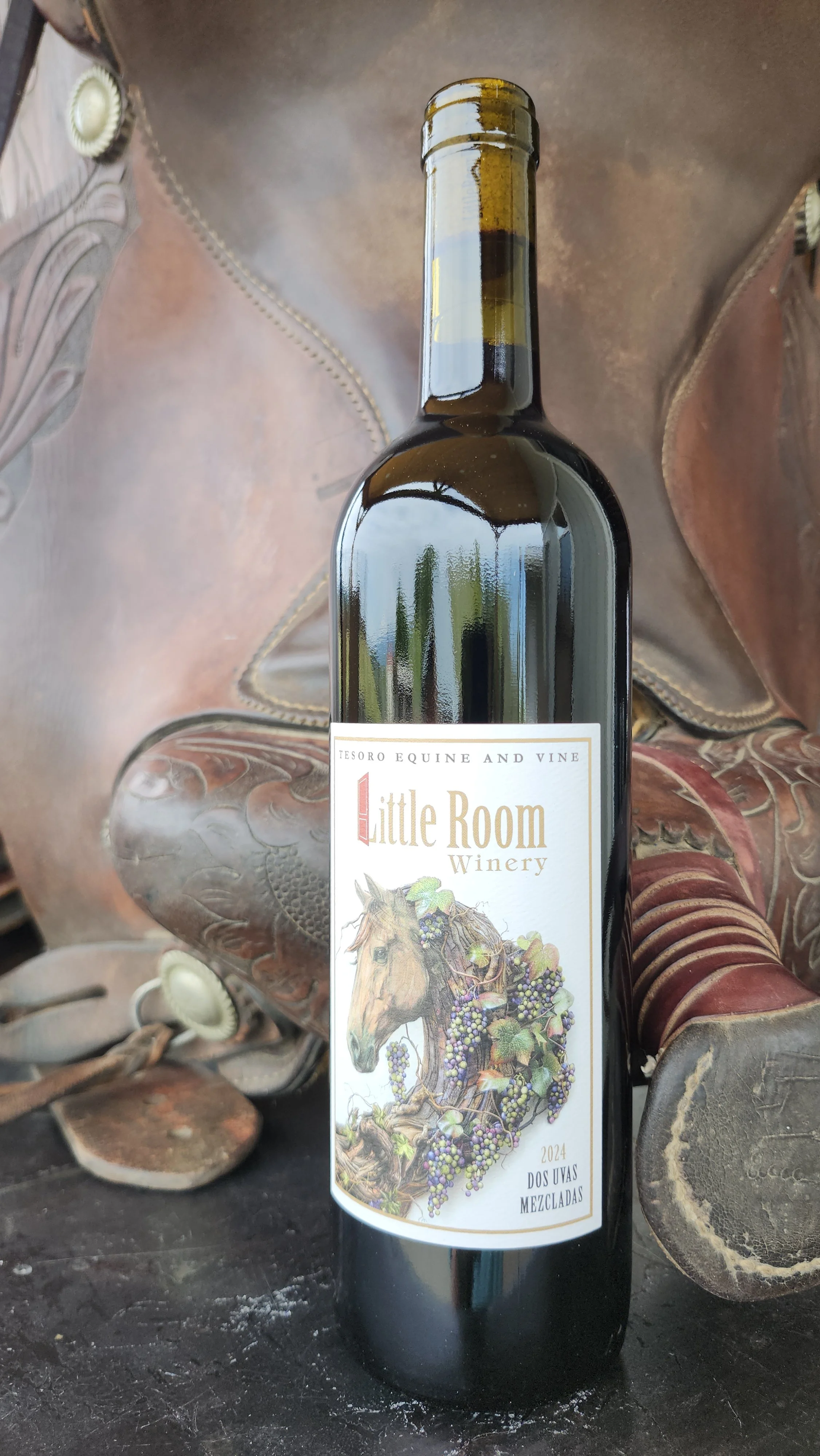 A wine bottle from Little Room Winery, featuring a label with an illustration of a horse surrounded by grapevines, placed among a saddle.