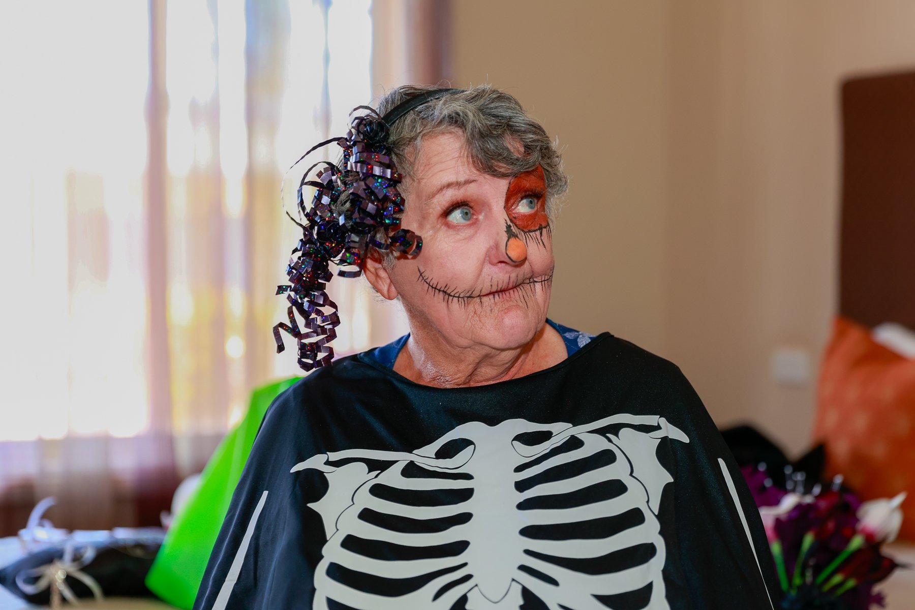 Older woman in Halloween makeup and skeleton costume.