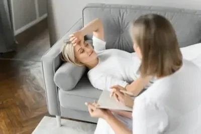 An image of a therapist undertaking RTT therapy sitting across from a client who is lying down, calm and quiet with eyes closed