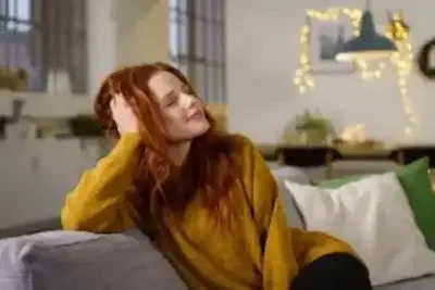 Young adult female relaxing on the couch feeling content in her calm and safe sober living environment