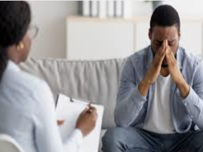 A man sitting with his head in his hands during a therapy session, conveying emotional struggle and the beginning of change.