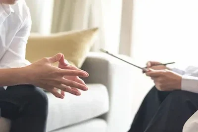 An image of one of our therapists working with a client sitting across from each other in an outpatient therapy session