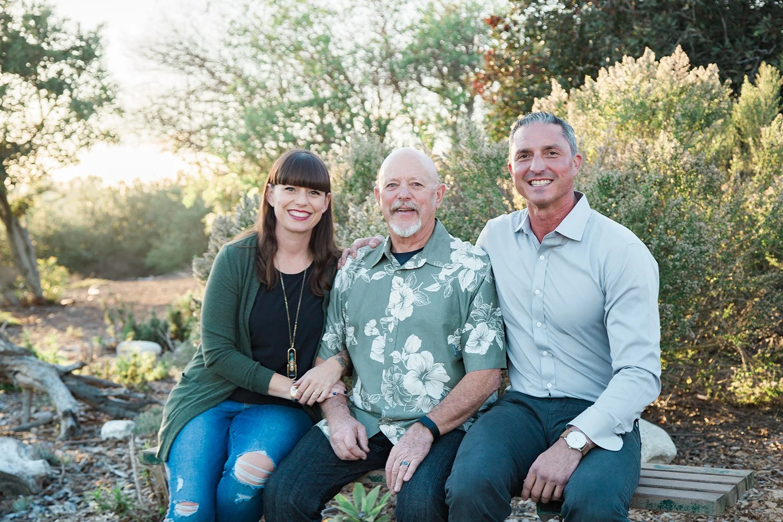 Siblings and their dad hugging and smiling for a photoshoot in a beautiful park, Urban Forest in Huntington Beach, CA
