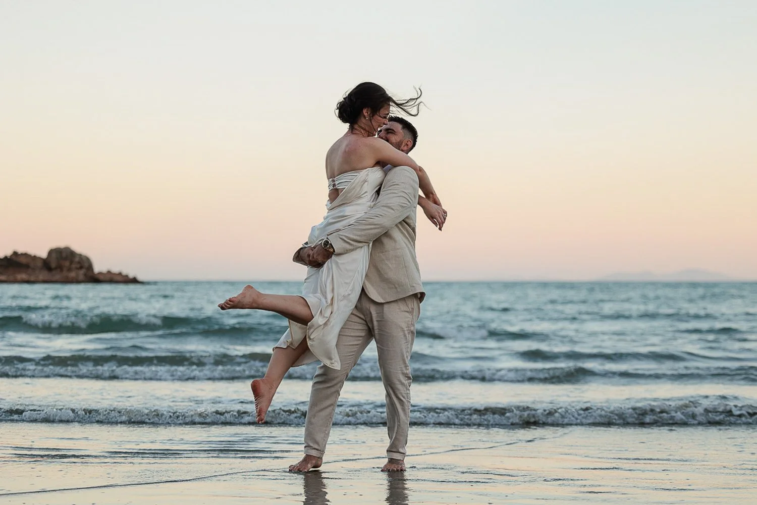 Groom lifting and twirling bride on Cape Hillsborough Beach