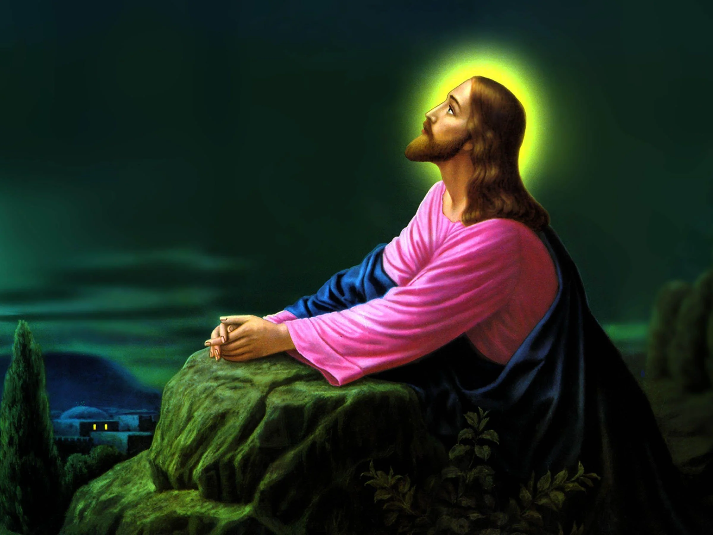 An artistic depiction of Jesus Christ with a glowing halo, kneeling on a rock with hands clasped and looking upward, with a dark sky and small village lights in the background.