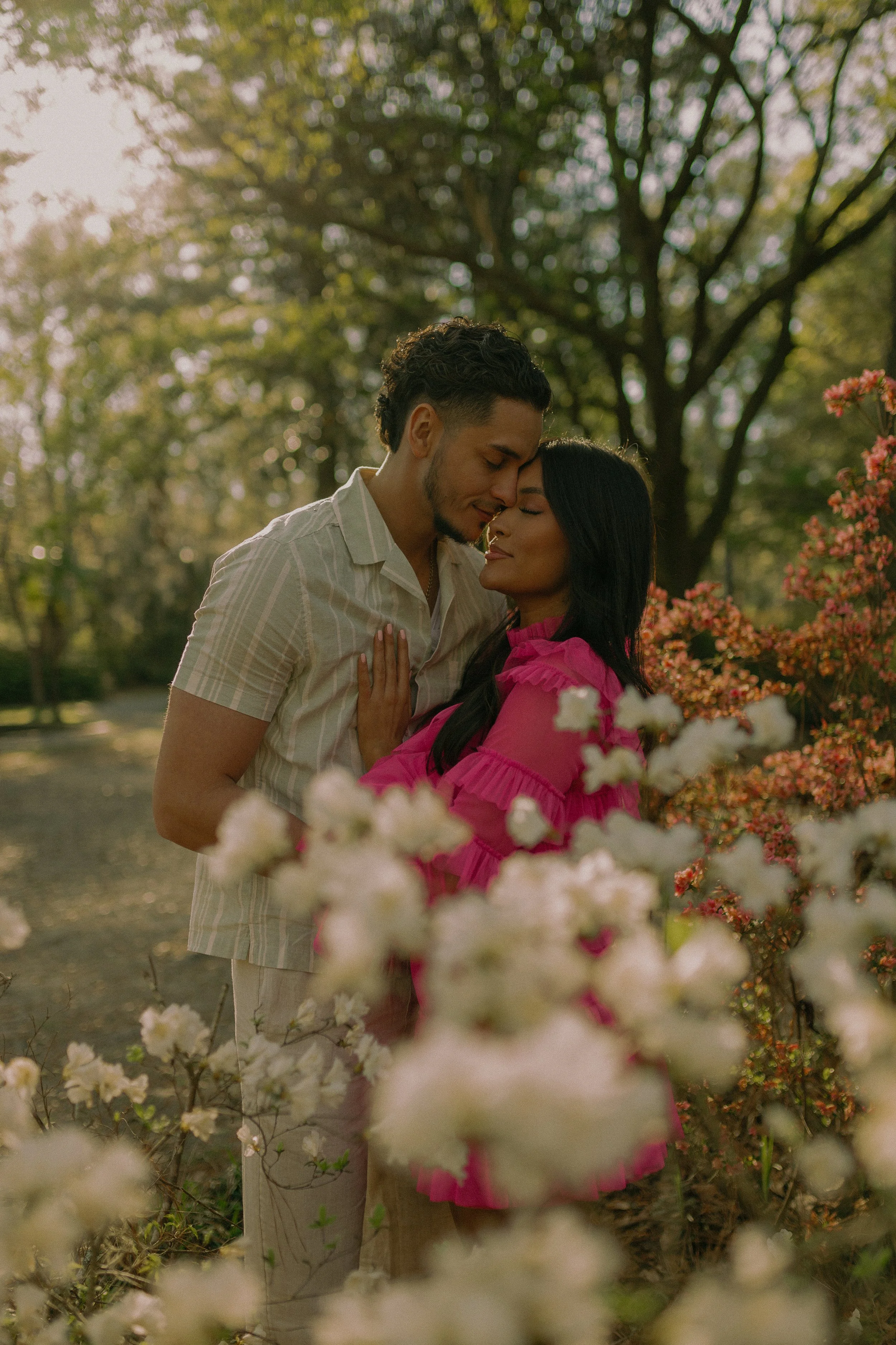 A couple embracing among flowering bushes in a garden.