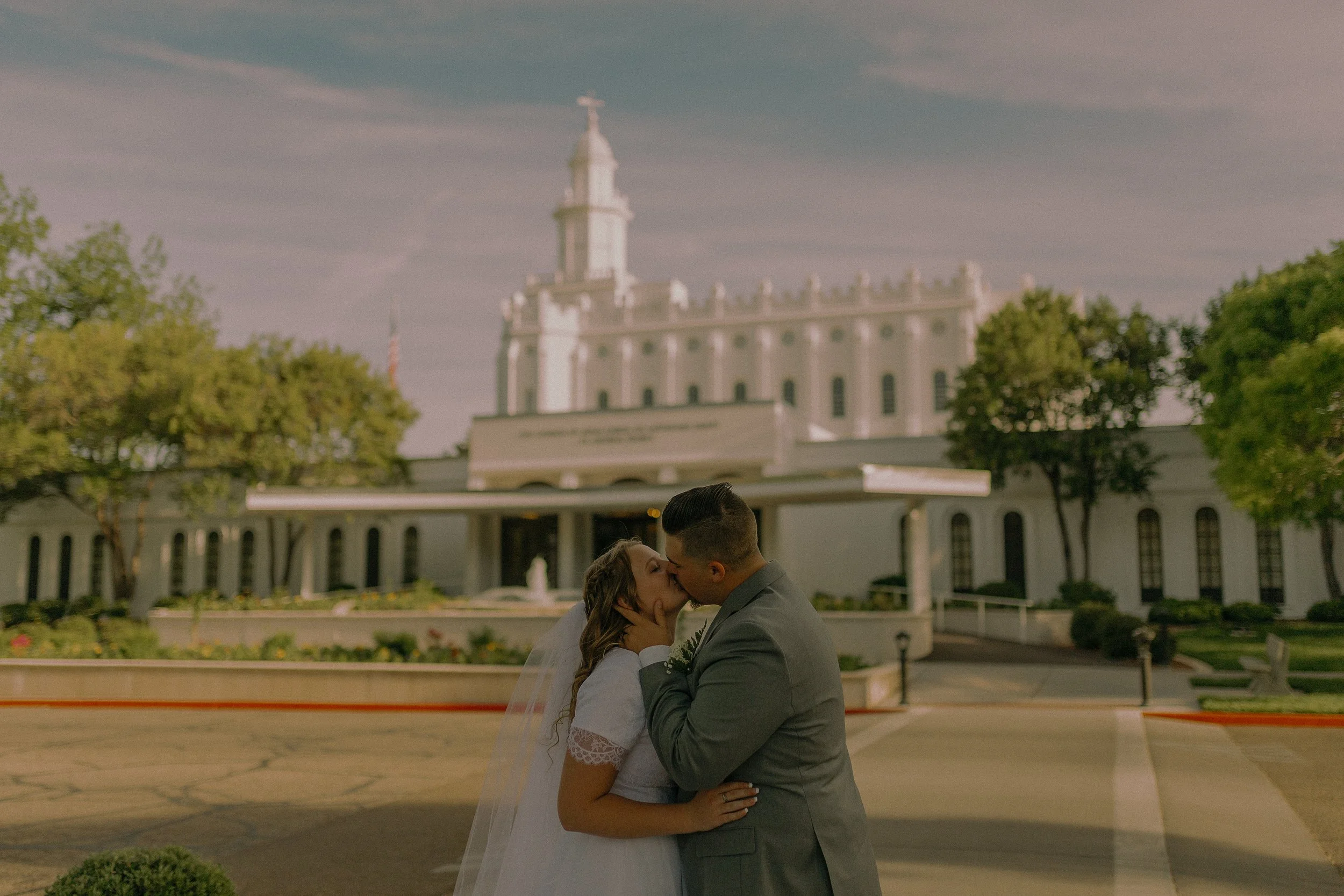 Married couple kissing in front of a church.