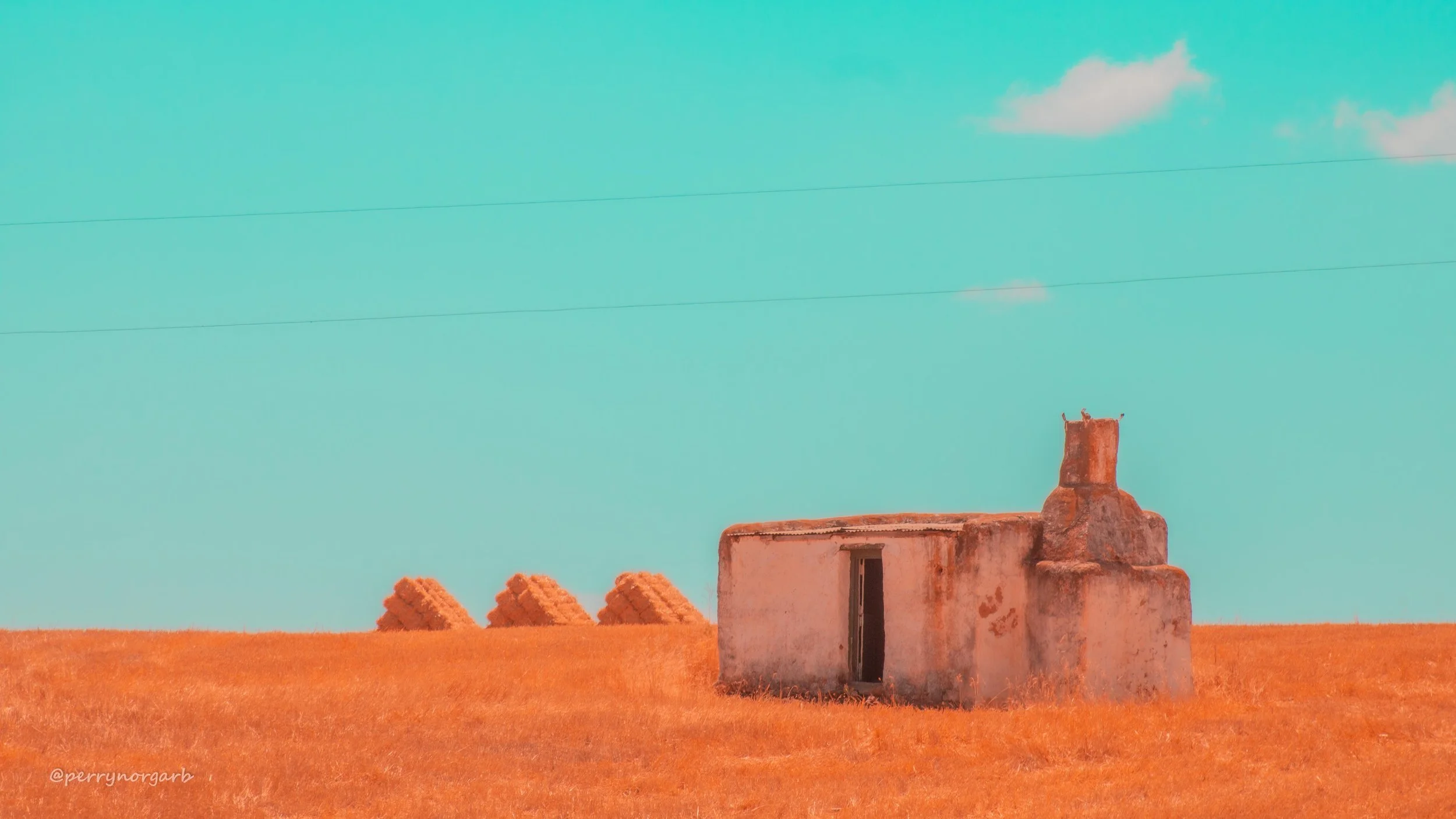 Triangular hay bale stacks, alongside an abandoned labourer's cottage.