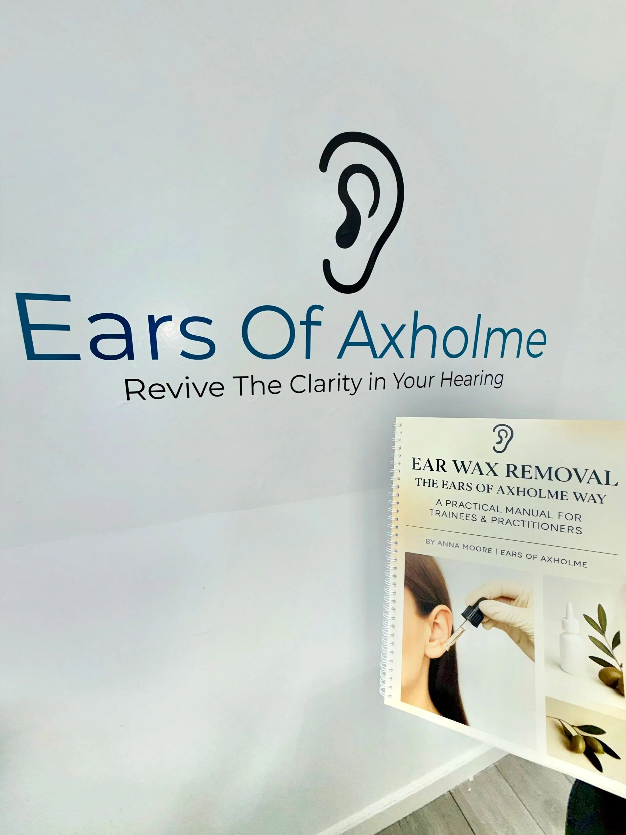 Sign for Ears of Axholme, a hearing clinic, with a graphic of an ear and a flyer about ear wax removal methods.