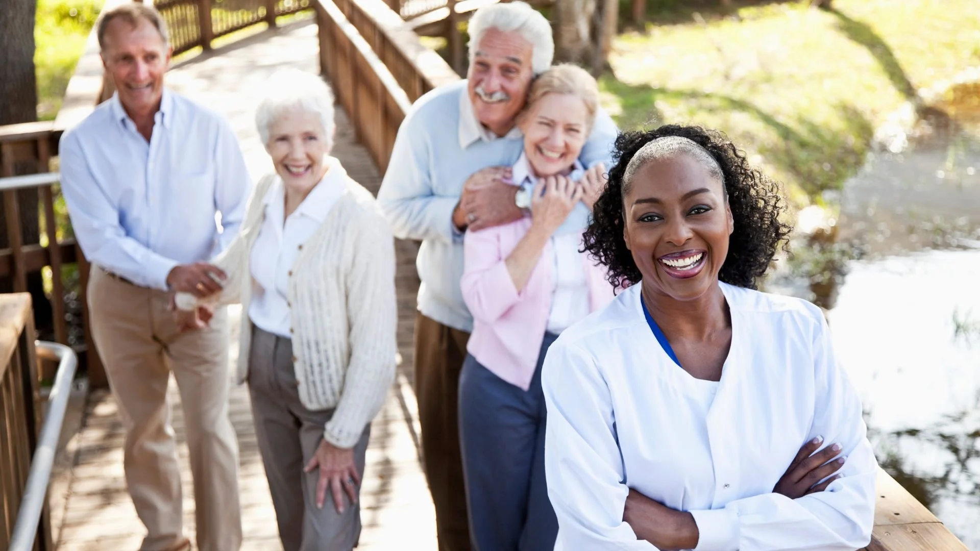 A nurse smiling with a group of happy elderly individuals on a walkway, showcasing short-term respite care in assisted living facilities.