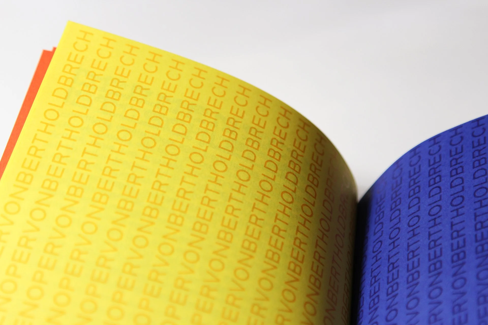 Bunte Papierbögen in den Farben Gelb, Orange und Blau, jeweils mit wiederholtem Text 'BERTHOLD BRECHT'.