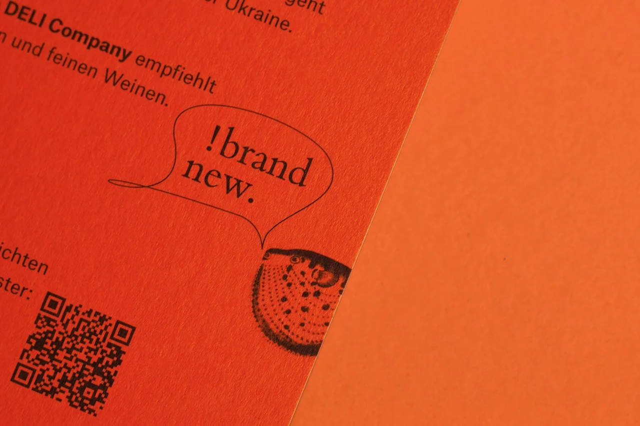 Ein orangefarbenes Plakat mit einem QR-Code, einem Cartoon-Häschen und dem Text '!brand new.' in einer Sprechblase.