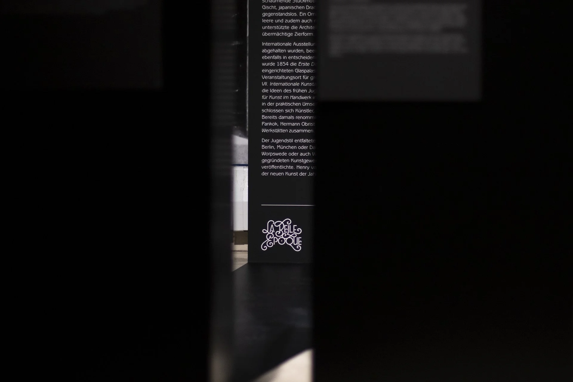 Ein schwarzes Informationsschild mit weißem Text und einem Logo bei La Belle Époque.