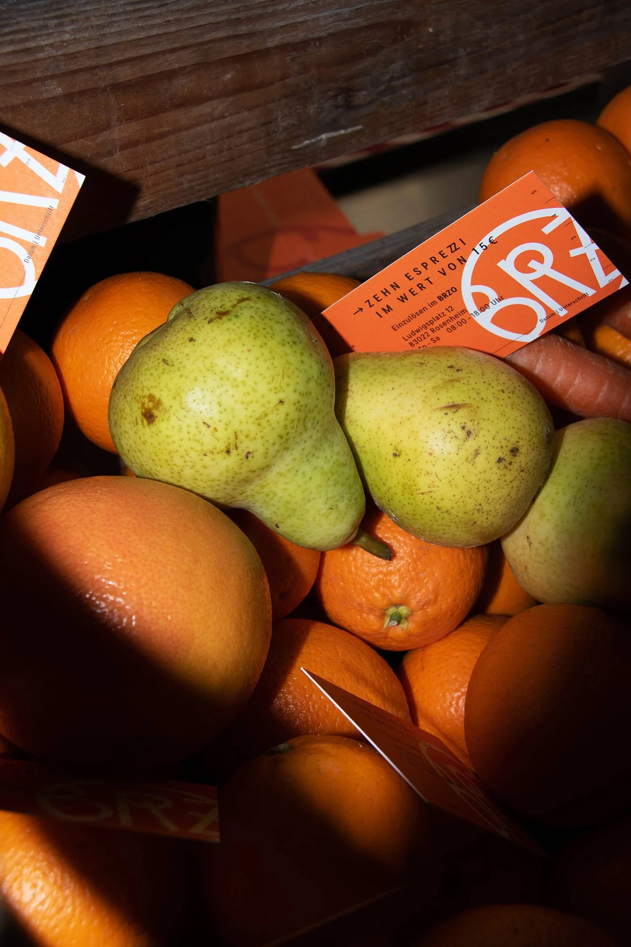 Grüne Birnen und Orangen in einem Korb mit einem orangefarbenen Preisschild.