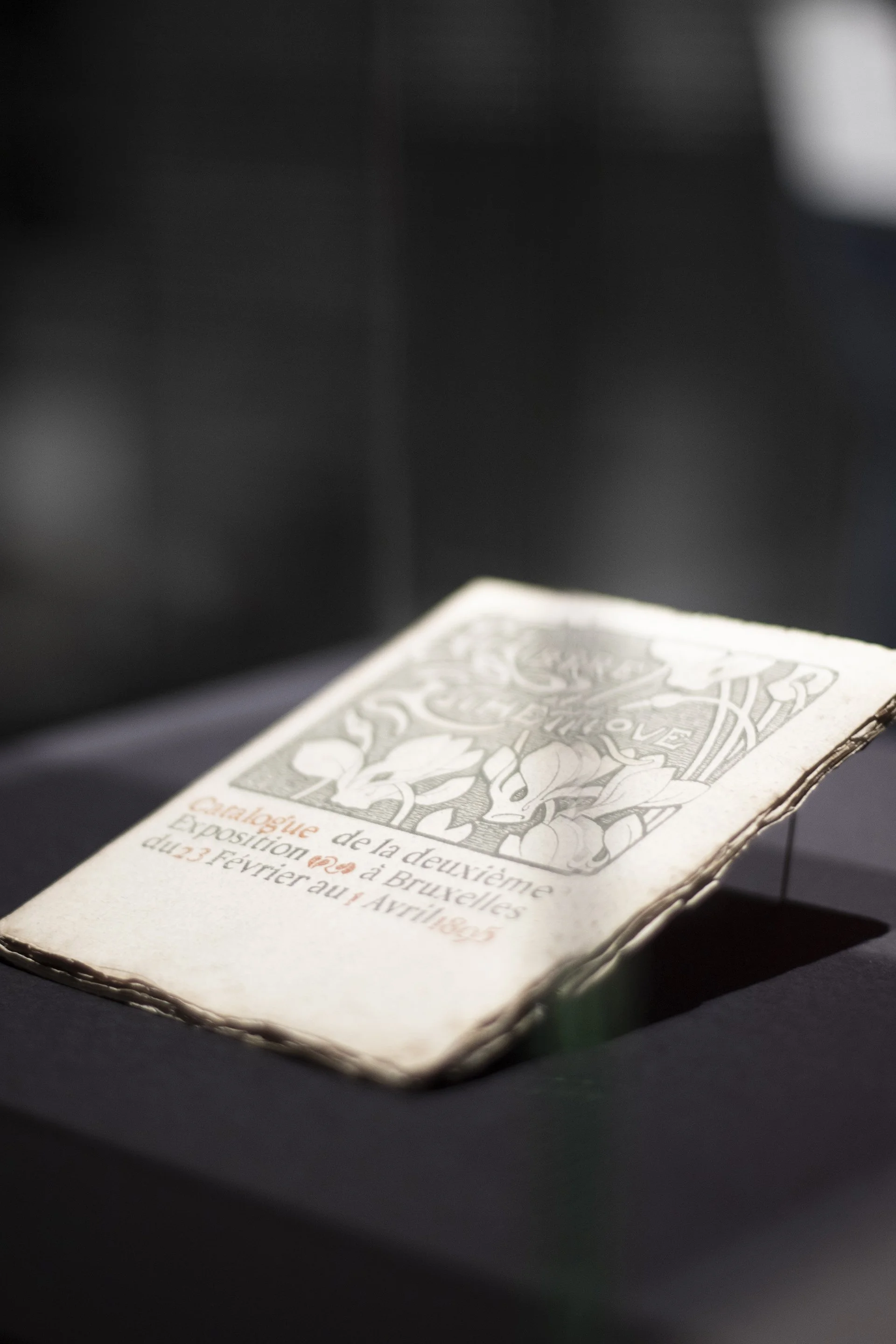 Ein altes, leicht zerknittertes Flugblatt über die Ausstellung der Zweiten Französischen Revolution in Brüssel vom 23. Februar bis 1. April 1895, mit einem grafischen Zitat und französischer Aufschrift.