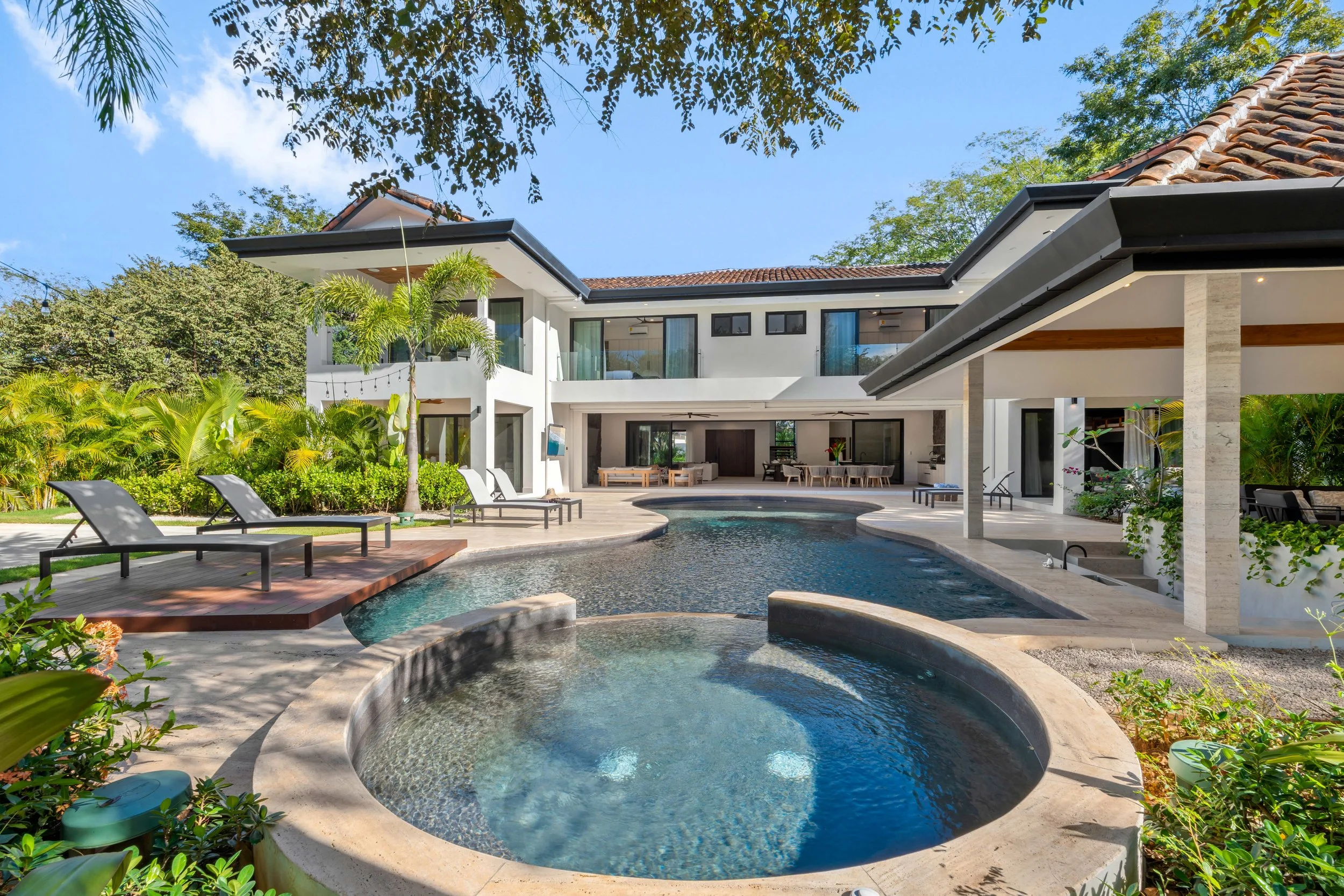 Luxury modern house with a pool and outdoor lounge area, surrounded by tropical greenery.