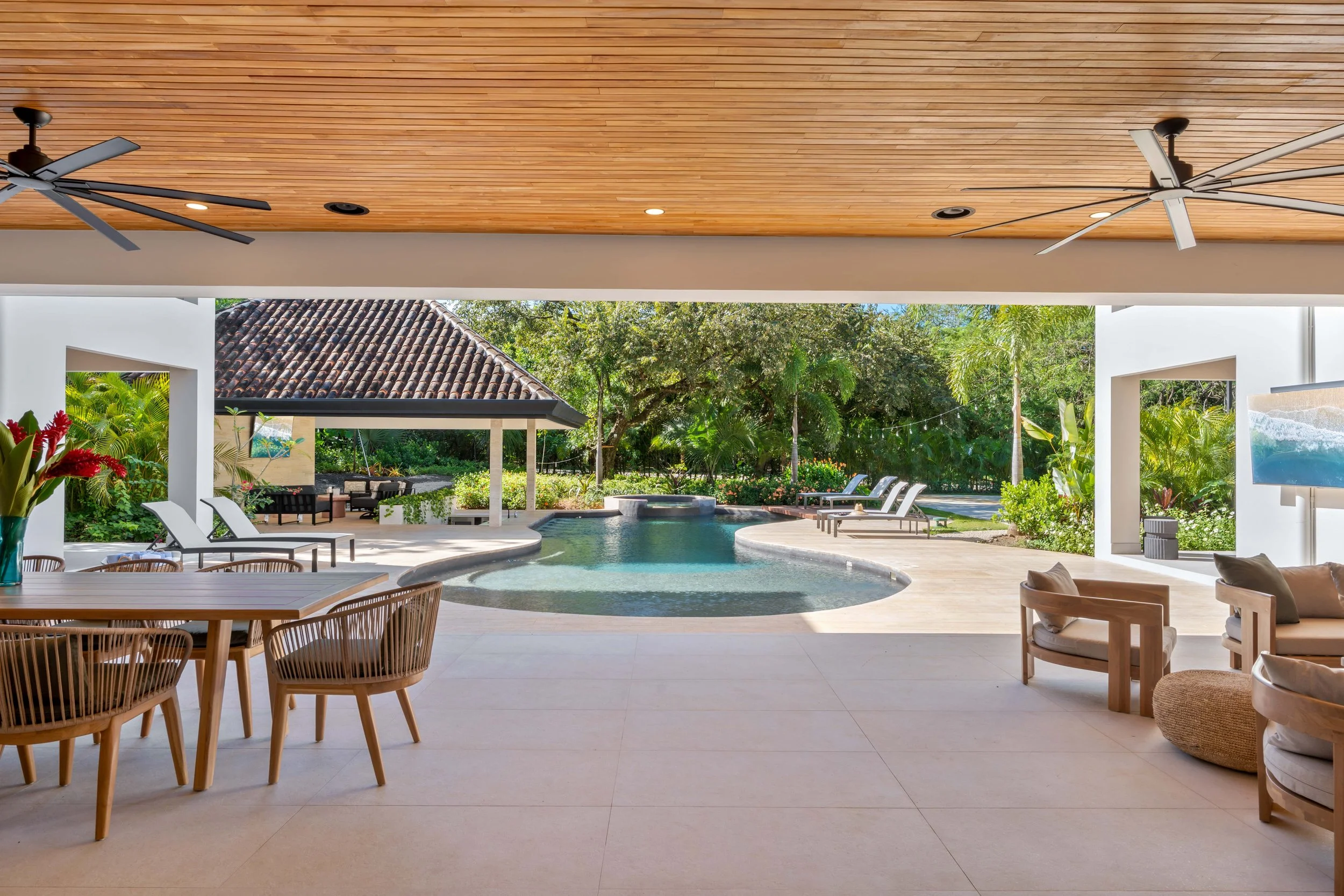 Open patio area overlooking a backyard pool with lounge chairs, lush greenery, and a gazebo in the background.