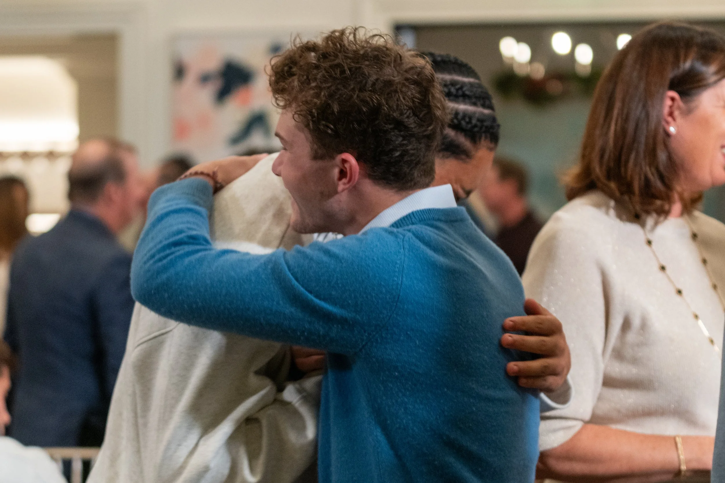 People hugging at a social gathering indoors