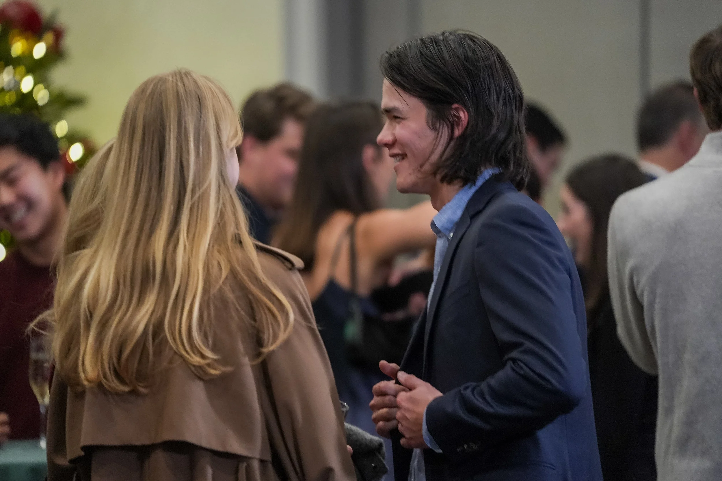 People socializing at a gathering with festive decorations in the background.