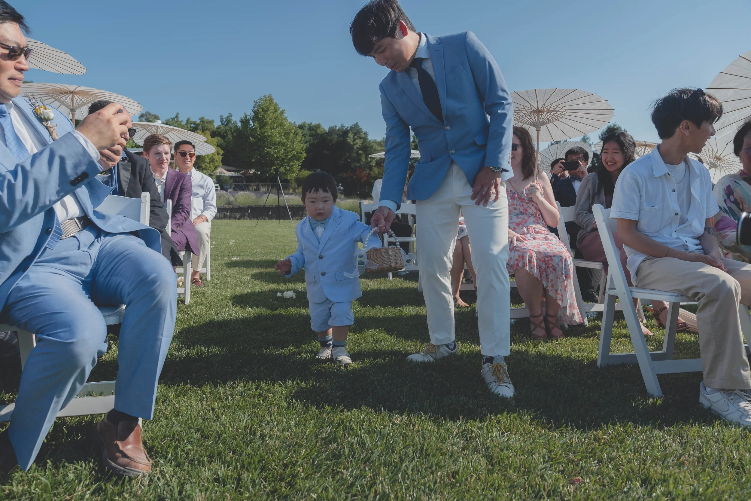 Guests smiling as the flower boy walks down the aisle in Sonoma.