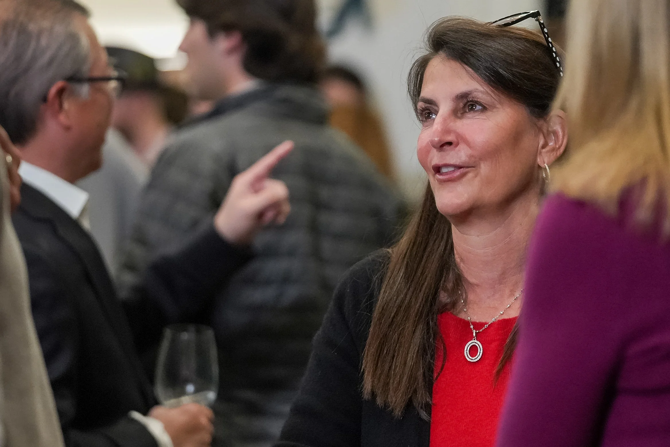 Woman in red dress talking at an indoor event with people in the background.