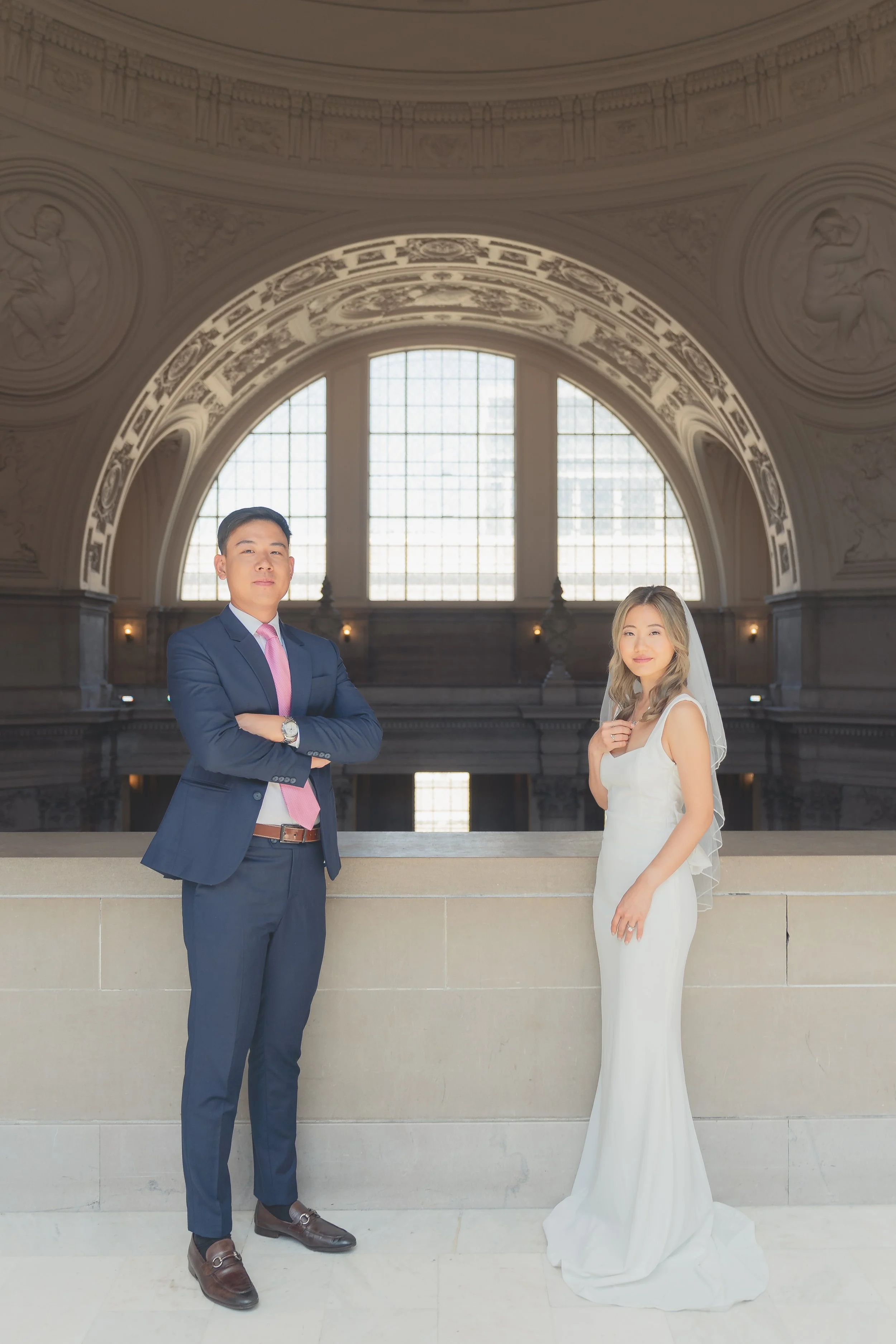 Wedding couple posing beneath the rotunda arches at San Francisco City Hall with soft natural light.