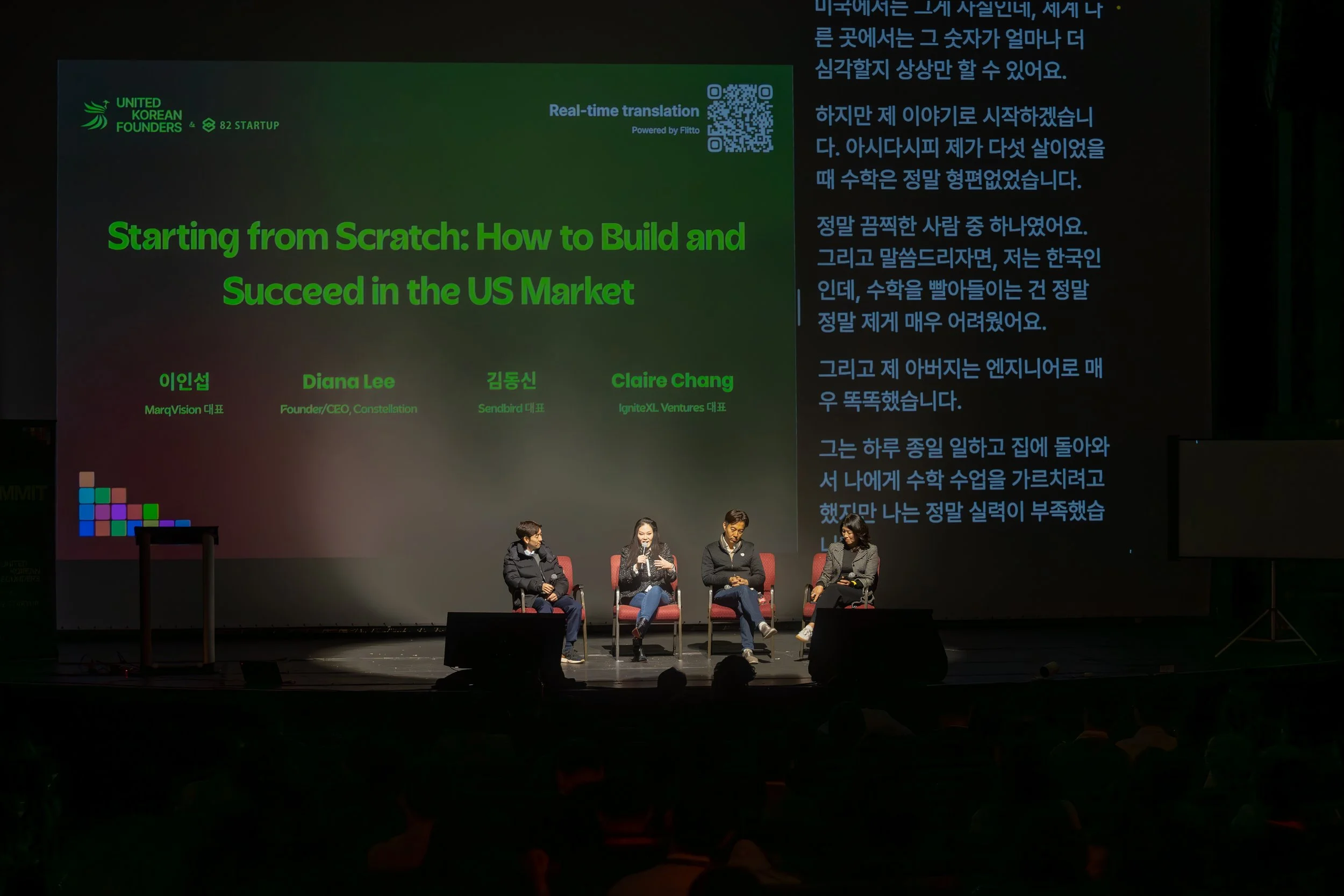 Panel discussion on stage titled 'Starting from Scratch: How to Build and Succeed in the US Market,' featuring four speakers seated and a screen displaying English to Korean translation.