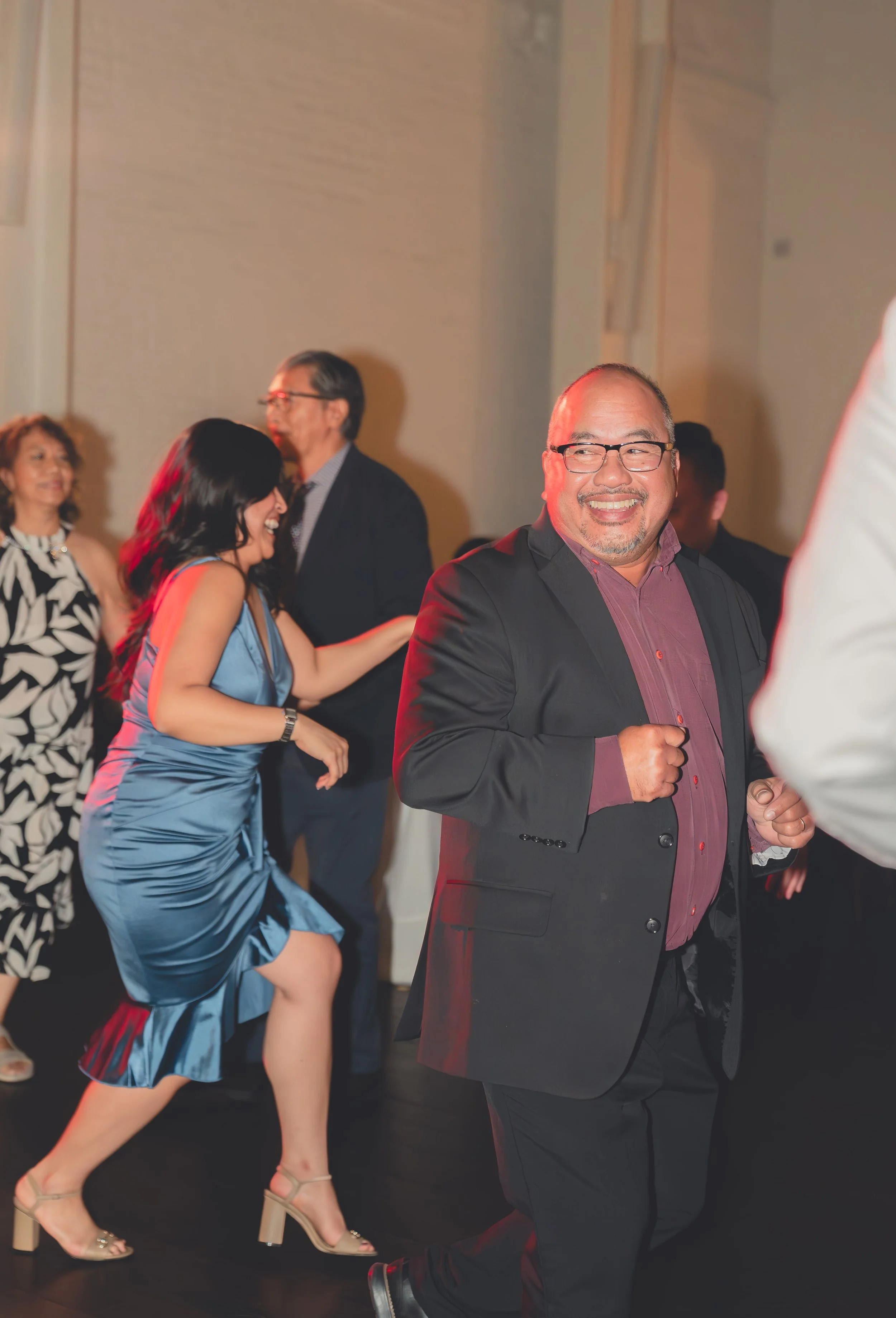 People dancing at a formal event, including a man in a suit and a woman in a blue dress.
