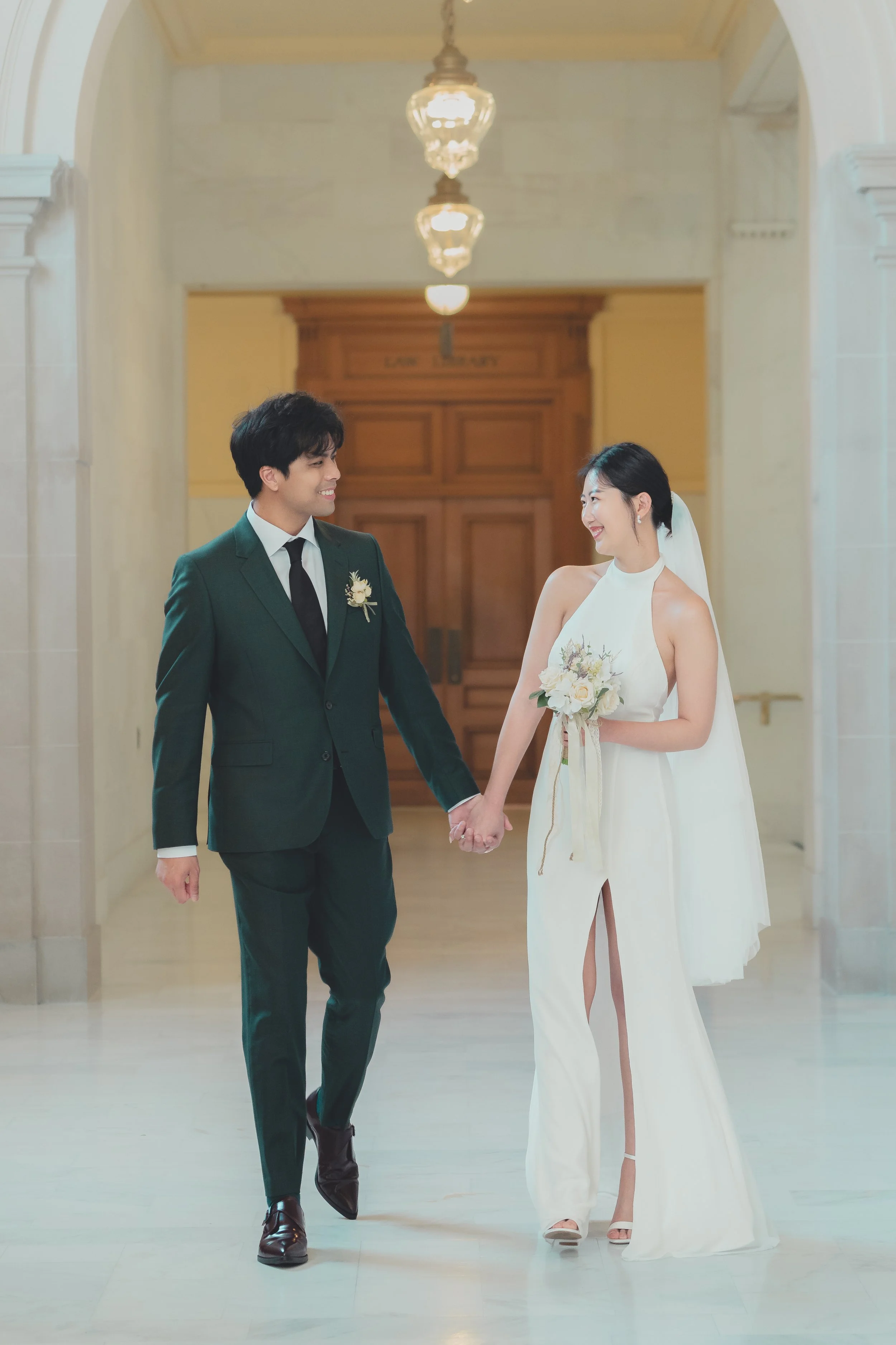 Bride and groom walking together inside San Francisco City Hall during an intimate wedding photoshoot.